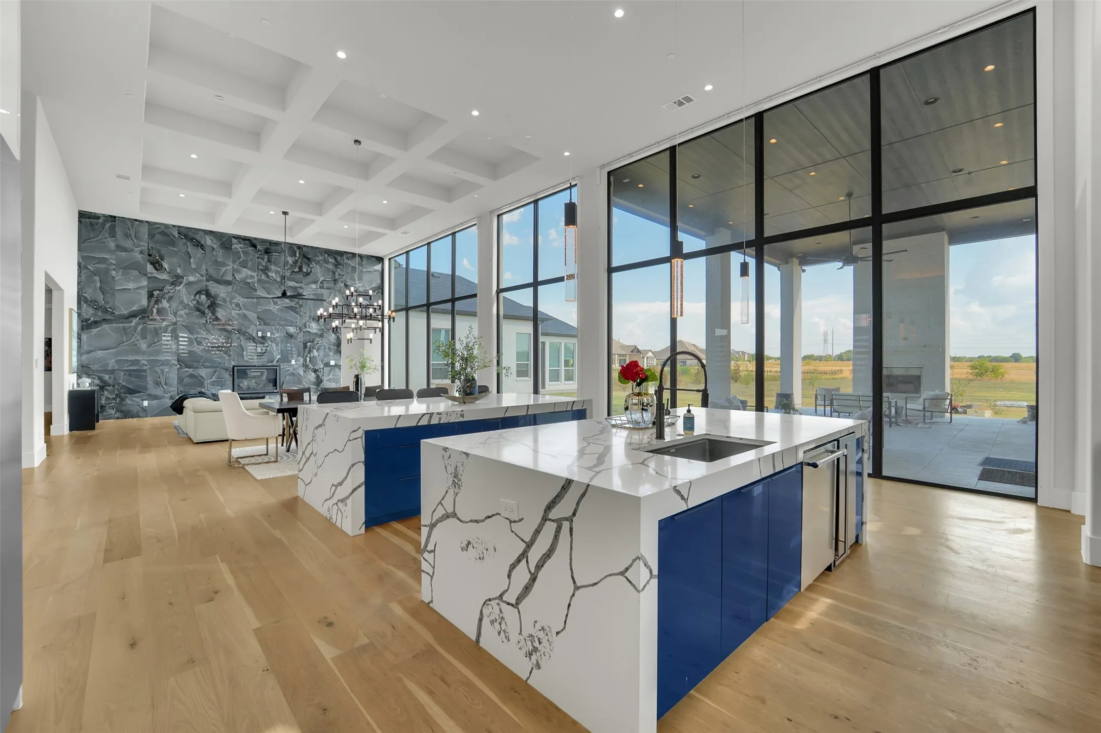 Expansive interior with light wood-finish flooring, a coffered ceiling, and a full-height stone accent wall