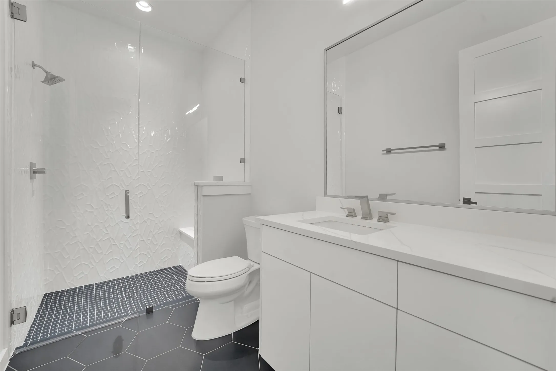 Walk-in shower with textured tile surround and glass enclosure