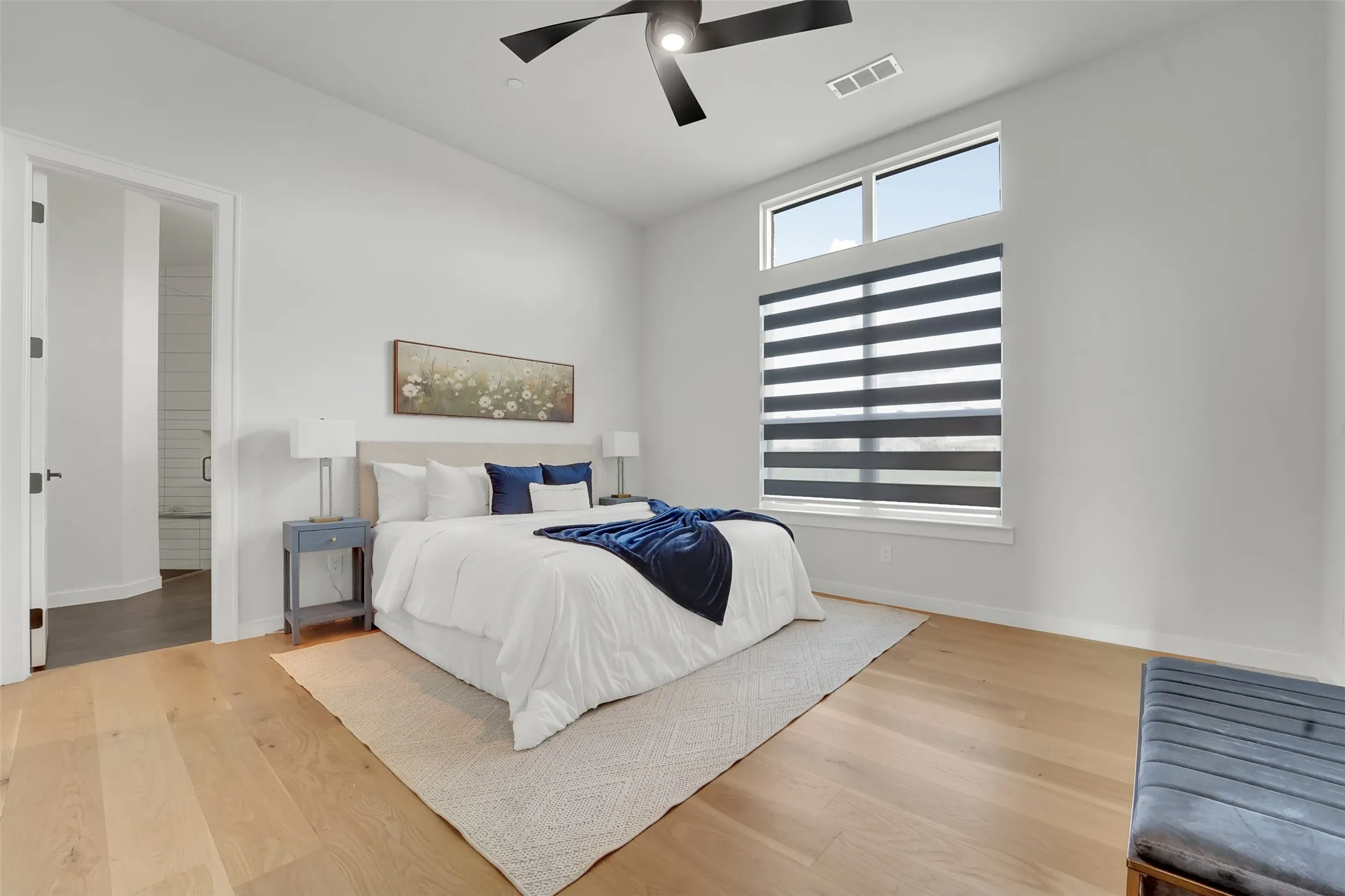 Wood-finish flooring, high ceilings, large window with upper transom, and a modern ceiling fan