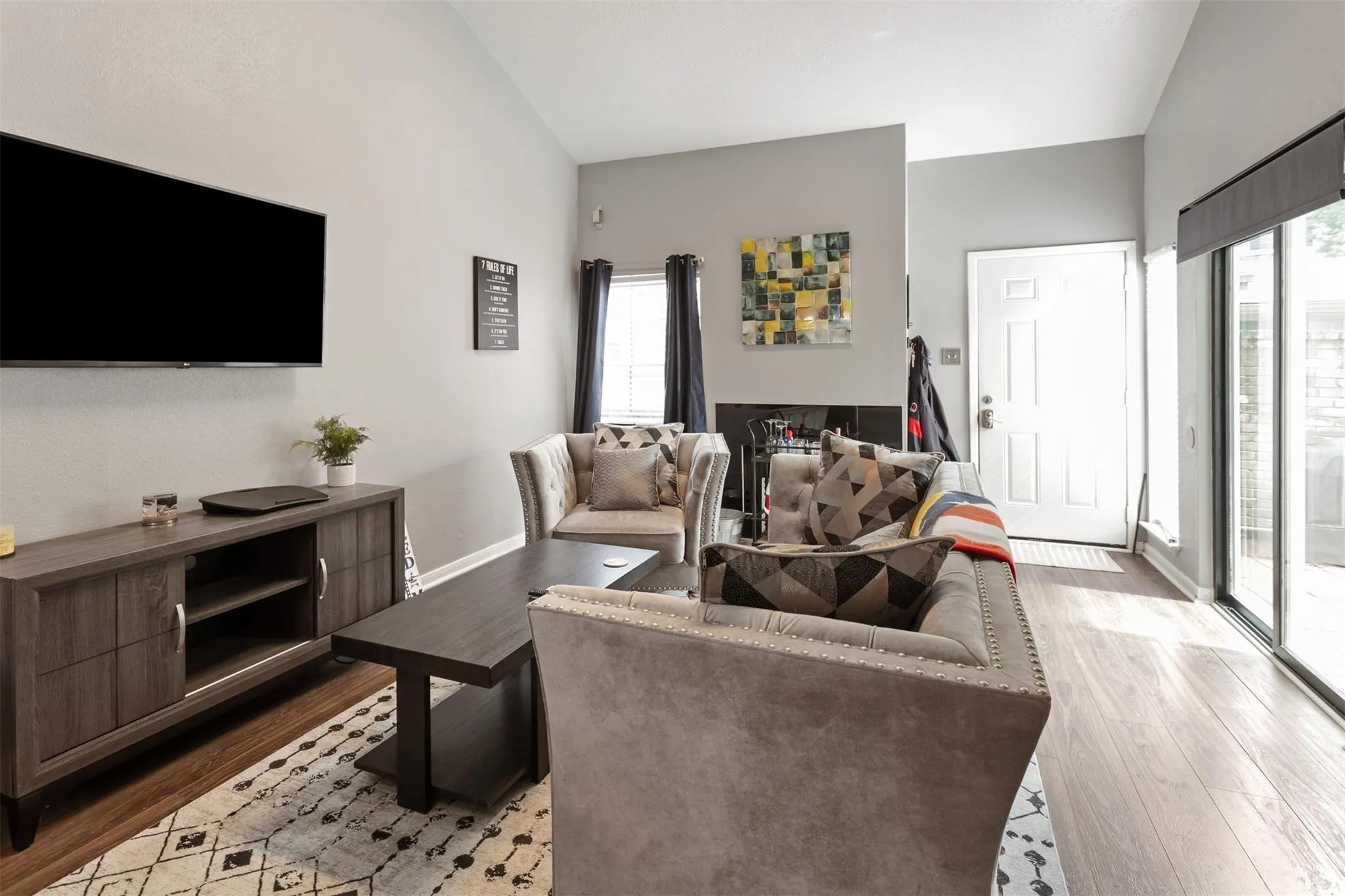 Vaulted ceiling, wood-finish flooring, sliding glass door, white paneled entry door, built-in shelving