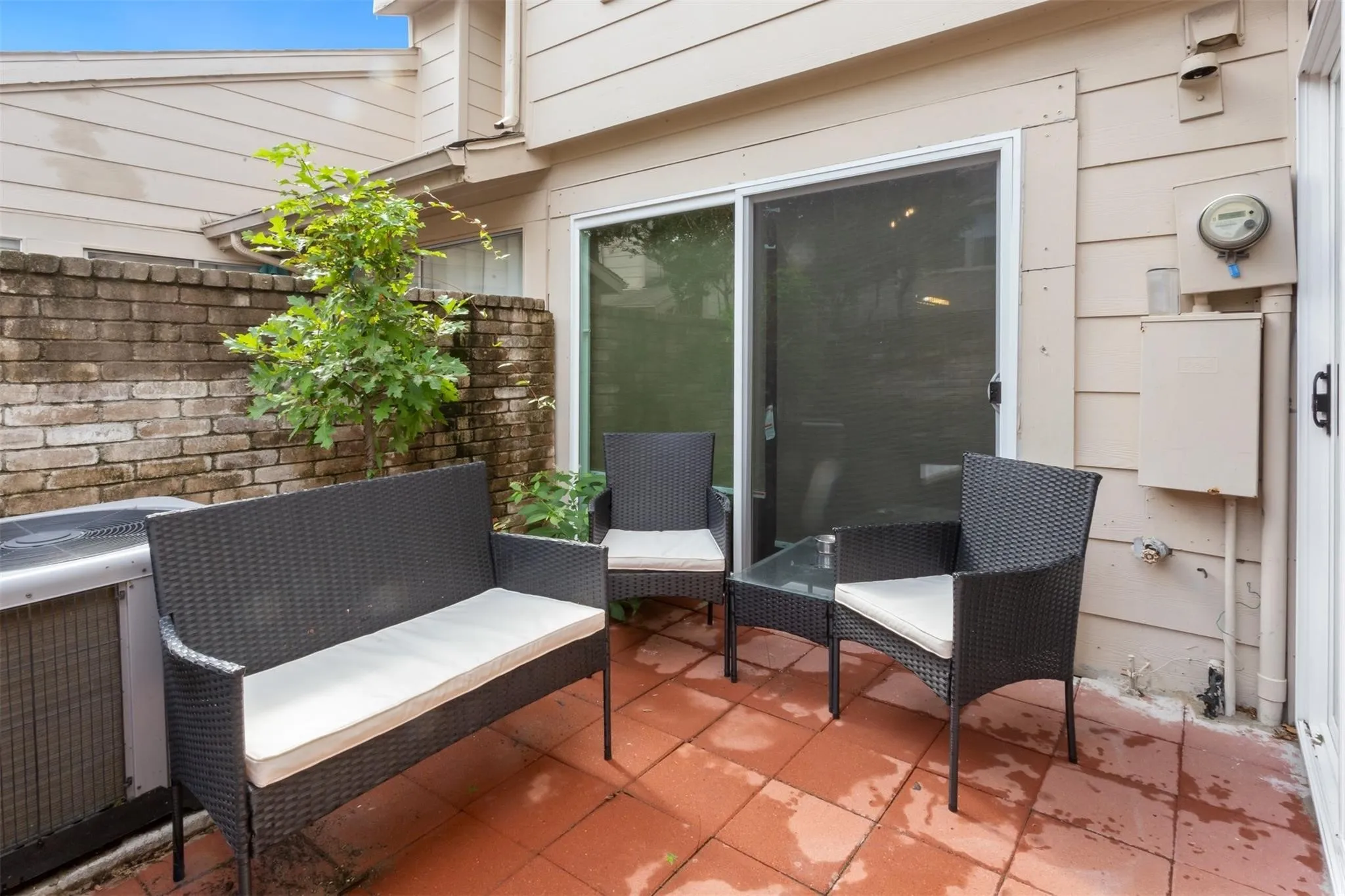 Private patio featuring terracotta-style pavers, a brick privacy wall, and sliding glass door access