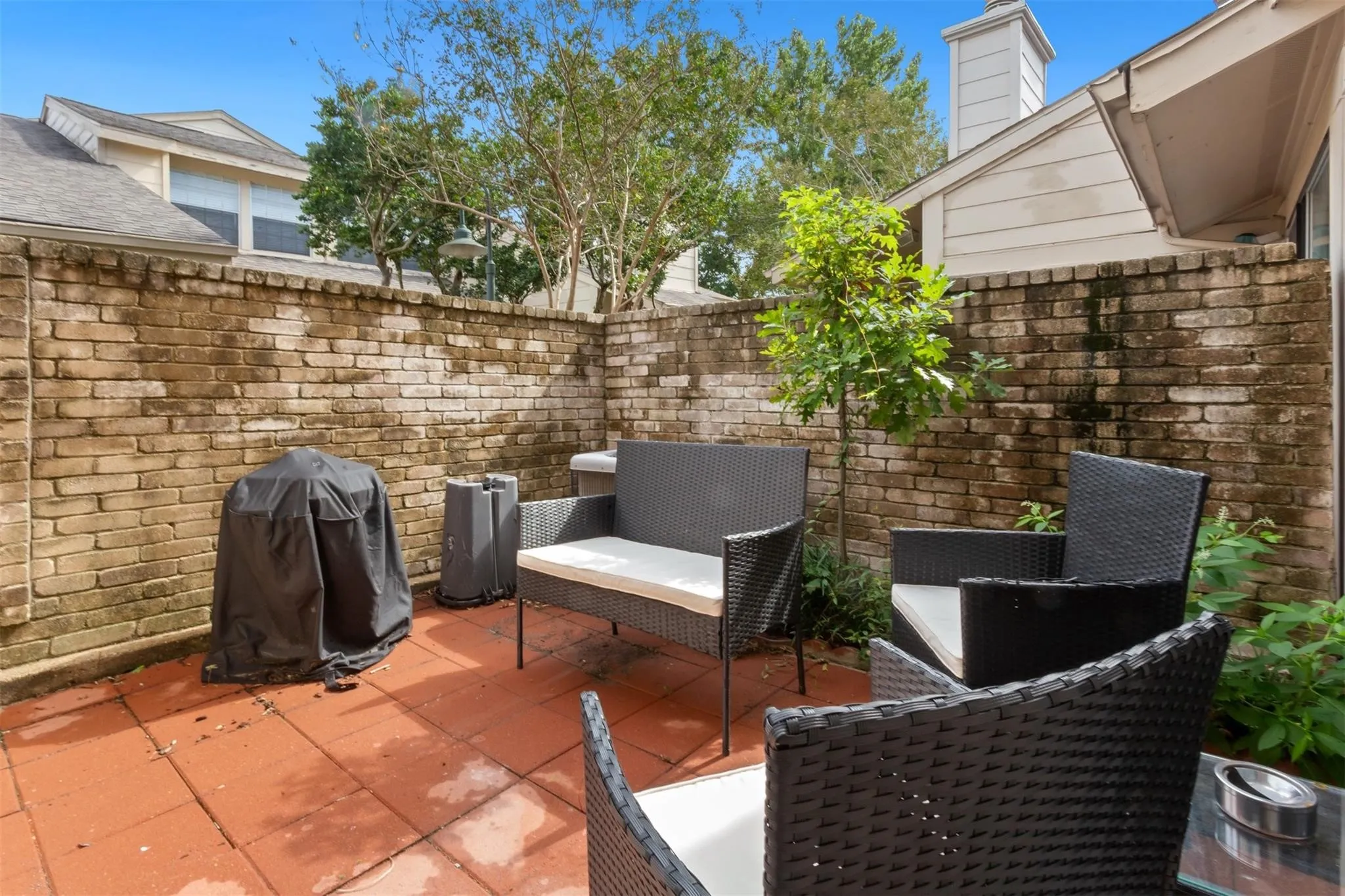 Private patio area featuring brick walls and red tile flooring
