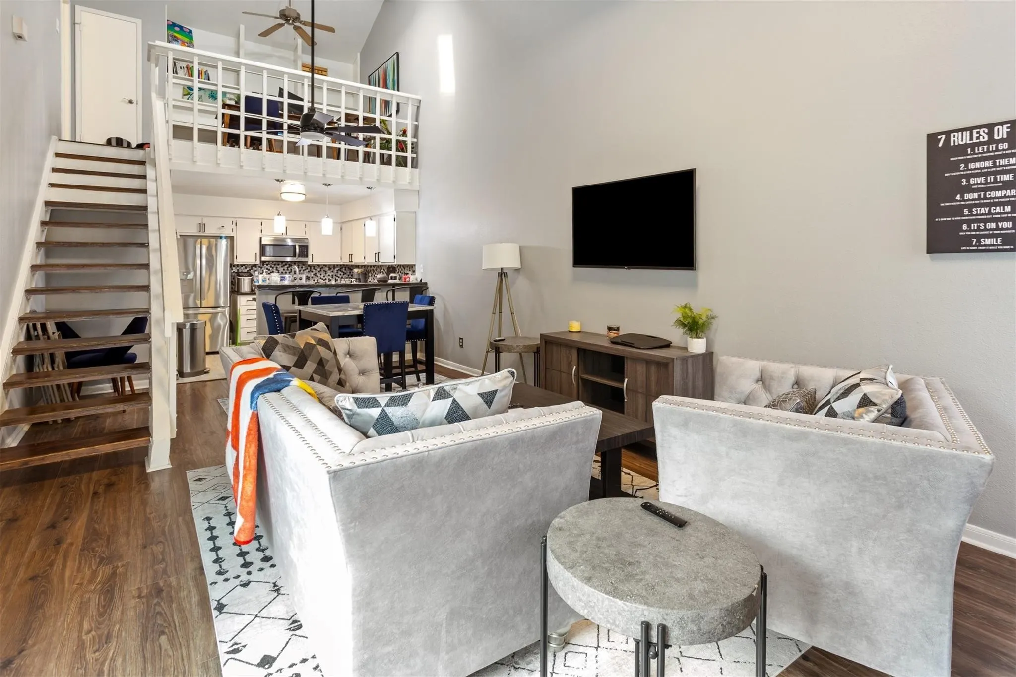 Soaring vaulted ceiling, wood-finish flooring, open-tread staircase, and a lofted space with a spindle railing