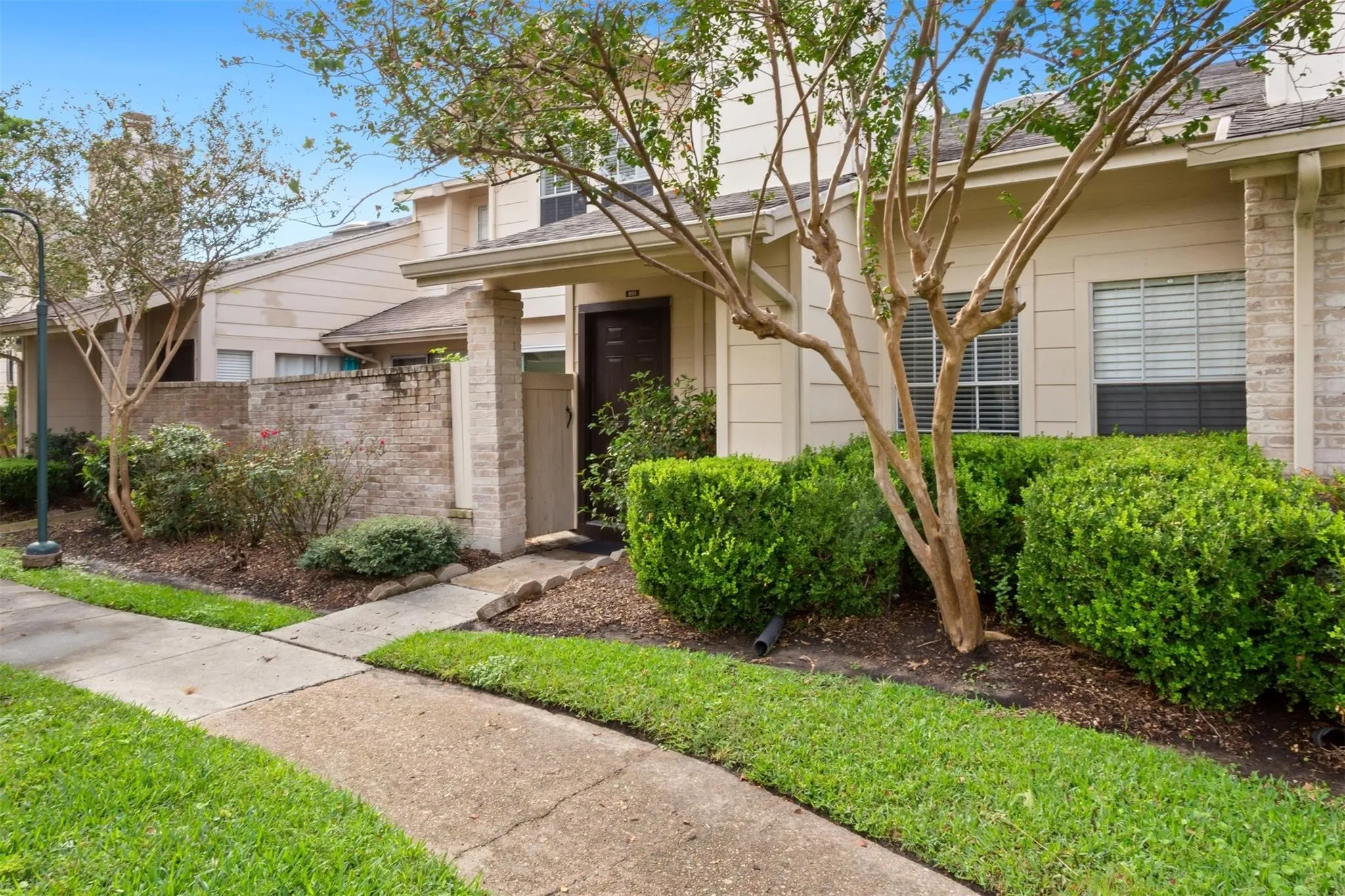 Exterior featuring brick and siding, established landscaping, and a concrete walkway