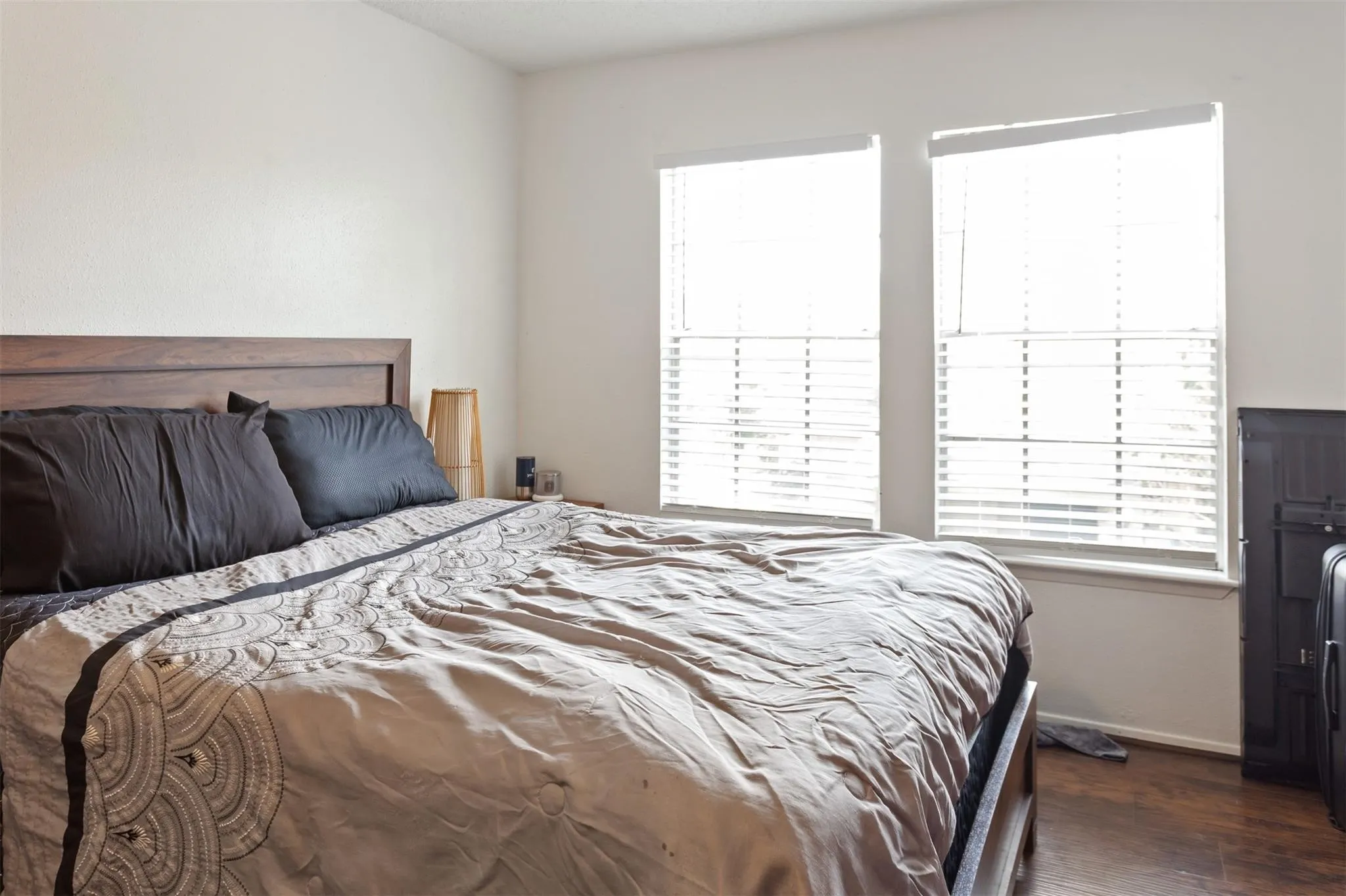 Bedroom 2 - Bright secondary bedroom featuring wood-finish flooring, plantation shutter-style window treatments, and abundant natural light from dual glass doors