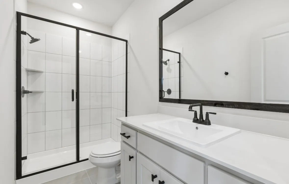 Frameless glass shower with matte black fixtures and built-in shelving