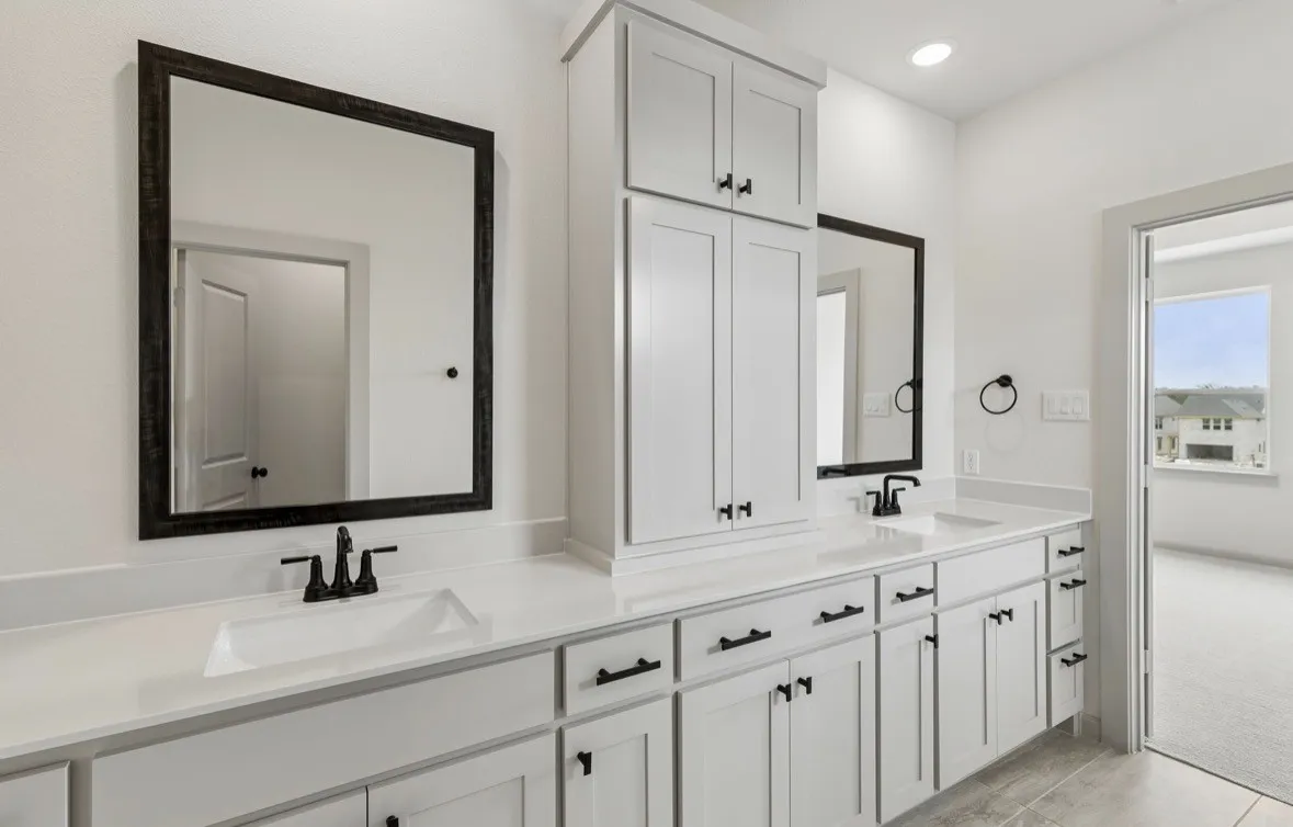 Dual vanity with integrated sinks, white cabinetry, a built-in storage tower, matte black hardware, and gray tile flooring