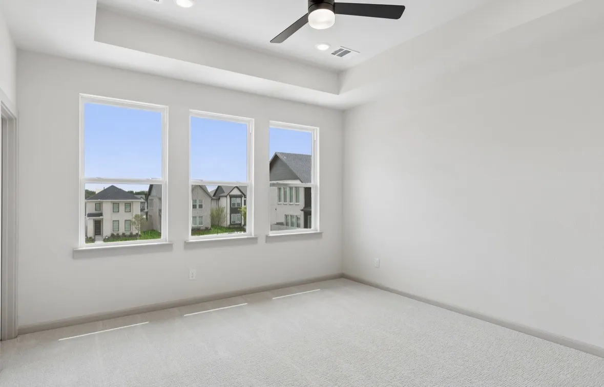 Tray ceiling with recessed lighting and a ceiling fan, three pane windows, and light-toned carpeting