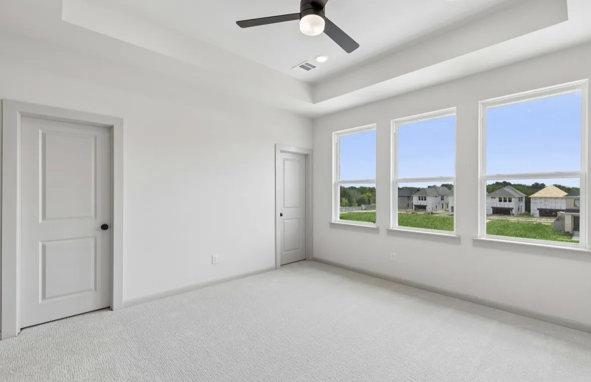 Tray ceiling with recessed lighting and a ceiling fan, three large windows, white paneled doors, and plush carpeting