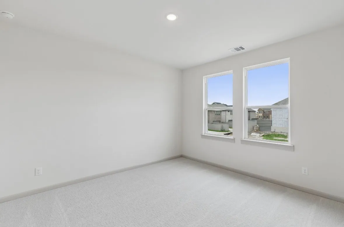 Recessed ceiling lighting, light gray wall paint, two large windows, white window trim, and light gray carpeting