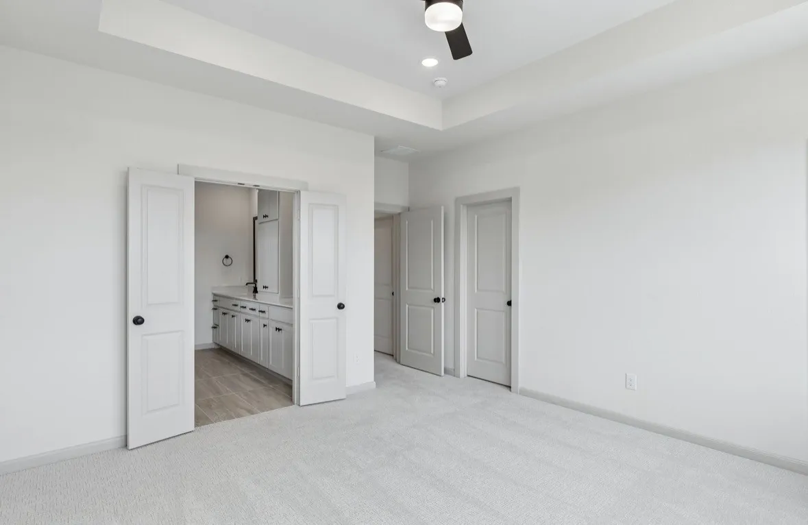 Recessed lighting, ceiling fan, tray ceiling, pocket doors, and light-toned carpeting