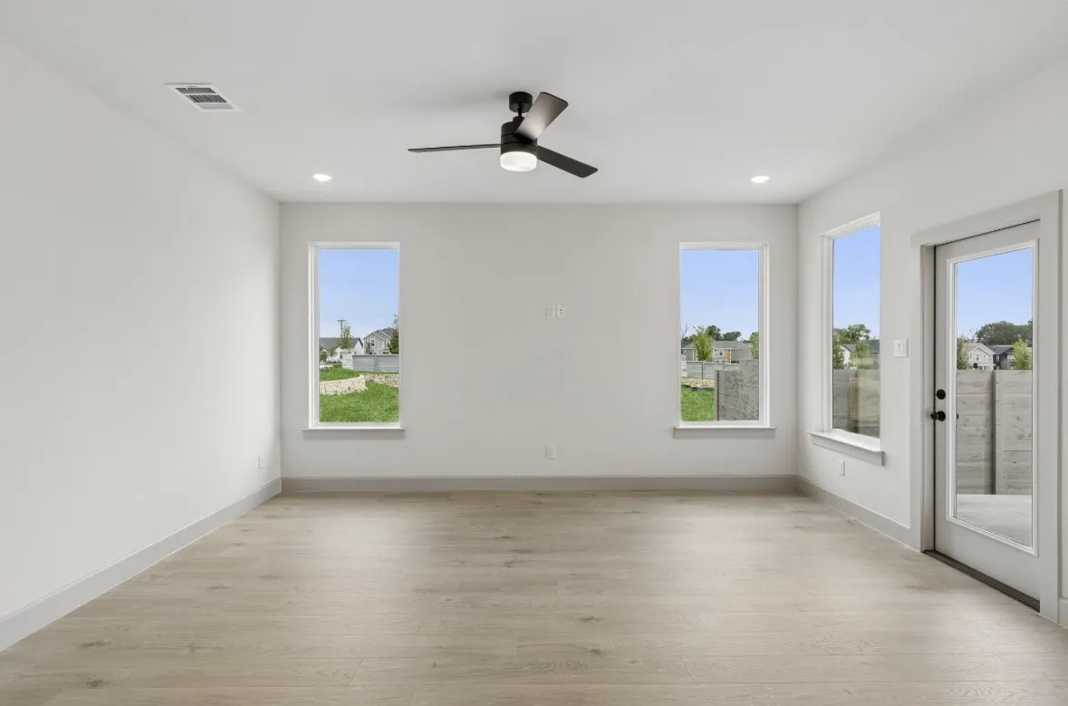 Wood-finish flooring, white walls, multiple windows, recessed lighting, and a ceiling fan with integrated lighting