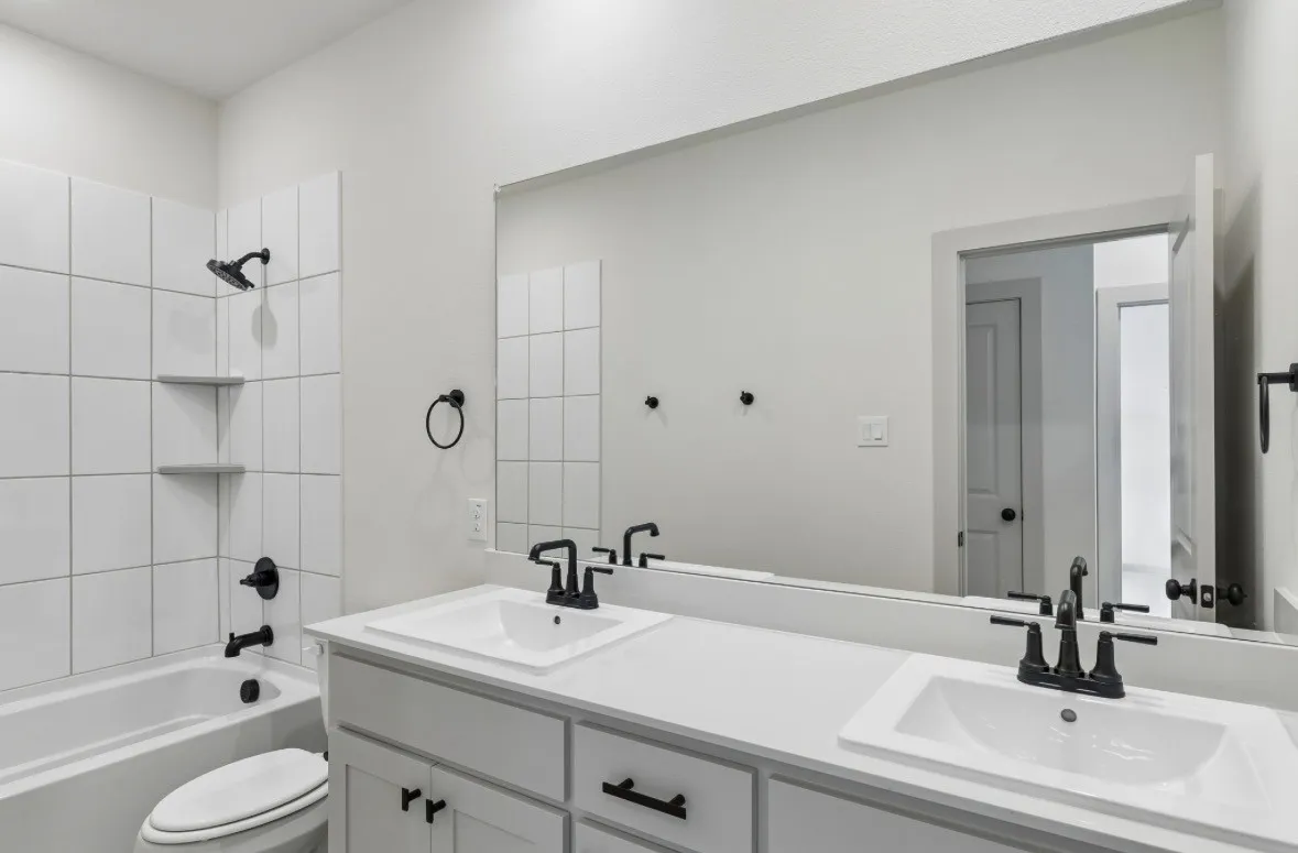 Dual vanity with integrated sinks and matte black fixtures, white countertop, and white shaker-style cabinetry