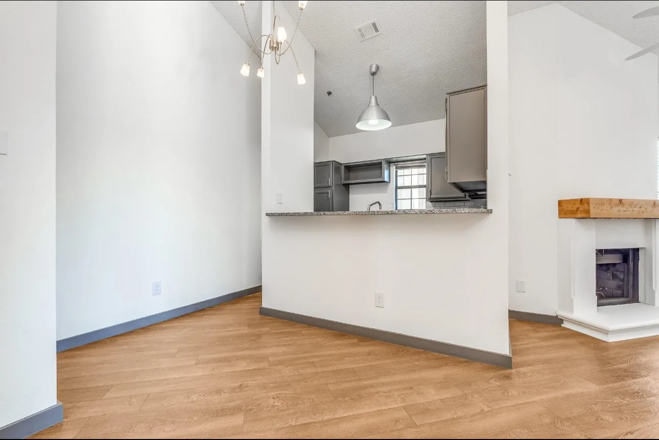 Kitchen with hanging light fixtures, a textured ceiling, light wood-type flooring, gray cabinets, and kitchen peninsula
