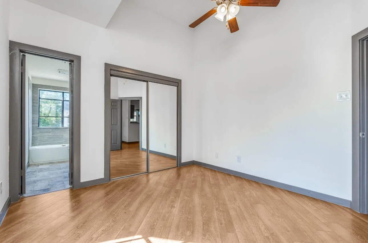 Unfurnished bedroom featuring ceiling fan, ensuite bathroom, light hardwood / wood-style floors, and a closet
