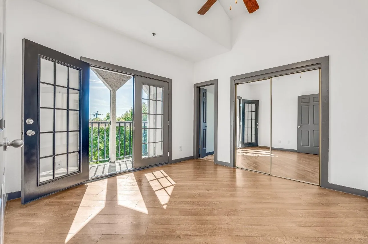 Unfurnished bedroom with a high ceiling, access to outside, ceiling fan, and light hardwood / wood-style flooring