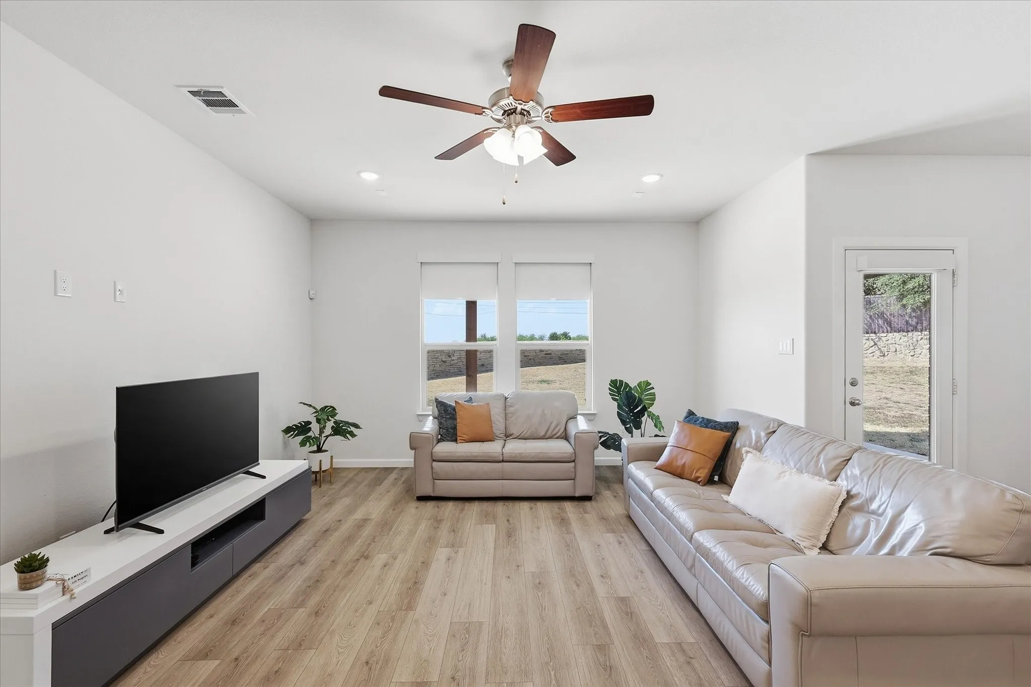 Recessed lighting, wood-finish flooring, ceiling fan, multiple windows, and exterior door with a window