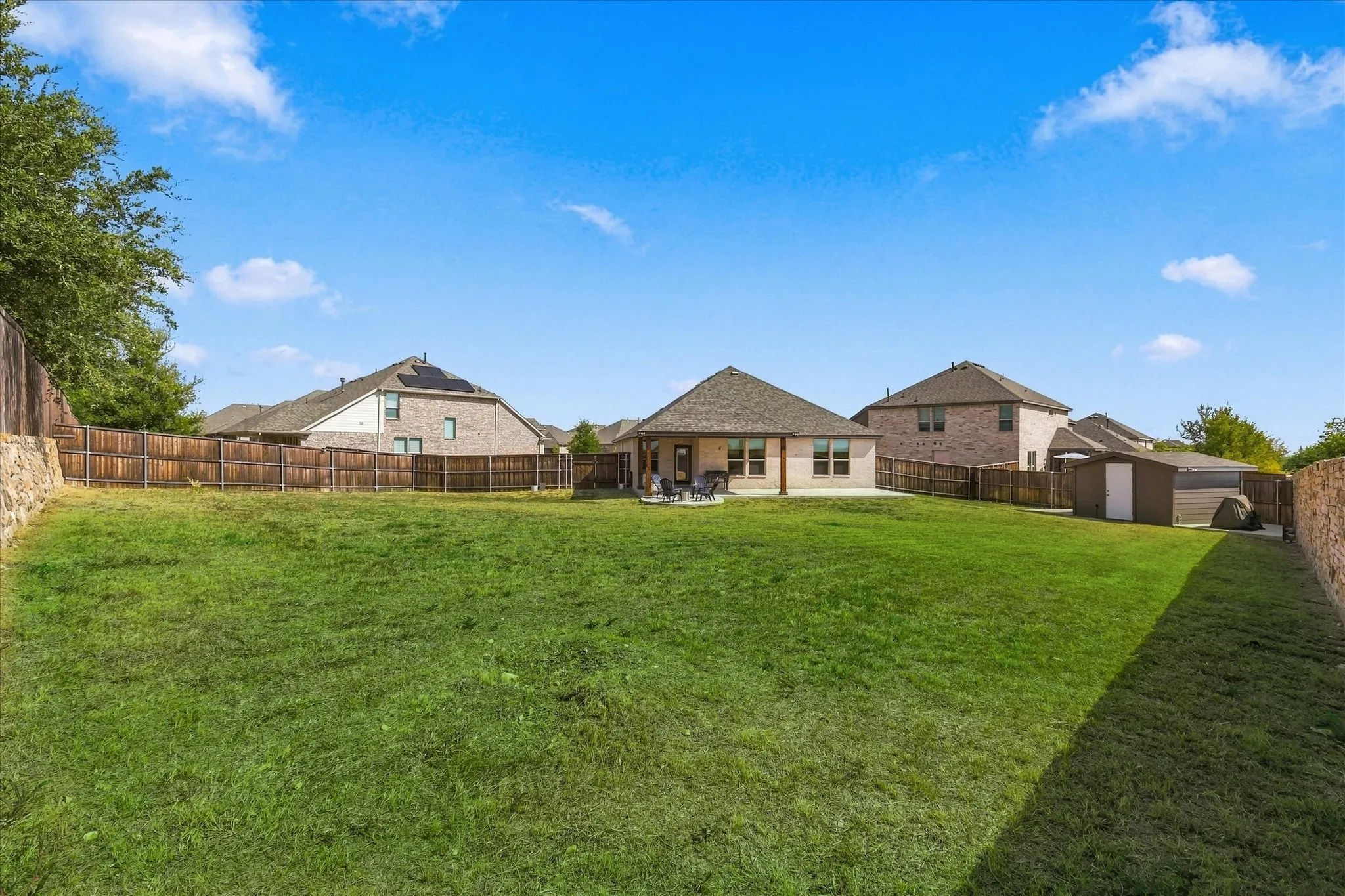 Expansive backyard with a covered patio, manicured lawn, and privacy fencing