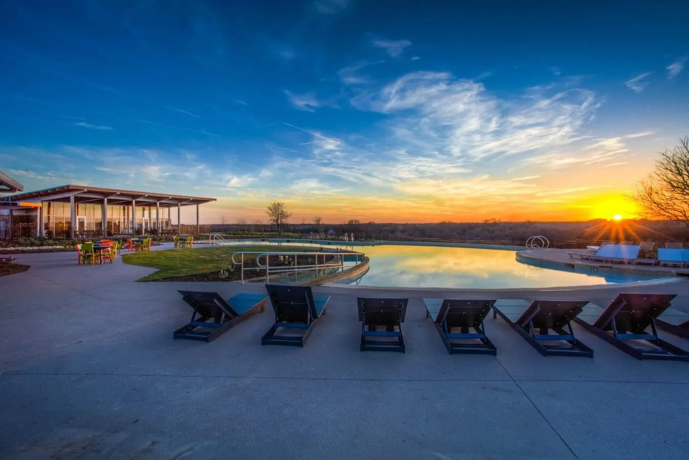 Expansive outdoor amenity area featuring a large swimming pool, concrete hardscaping, and a covered patio structure