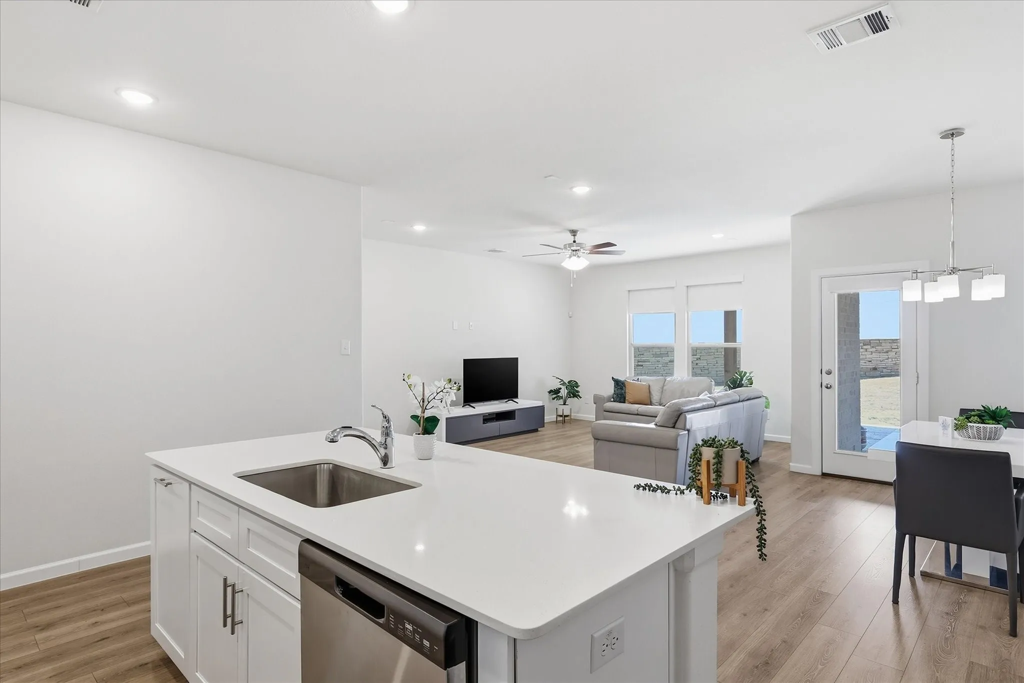 Kitchen island with a stainless steel sink, integrated dishwasher, and white cabinetry