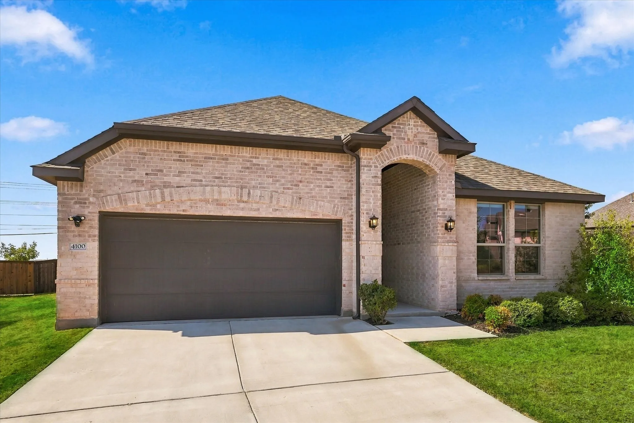 Brick exterior with an arched entryway, attached two-car garage, and a concrete driveway