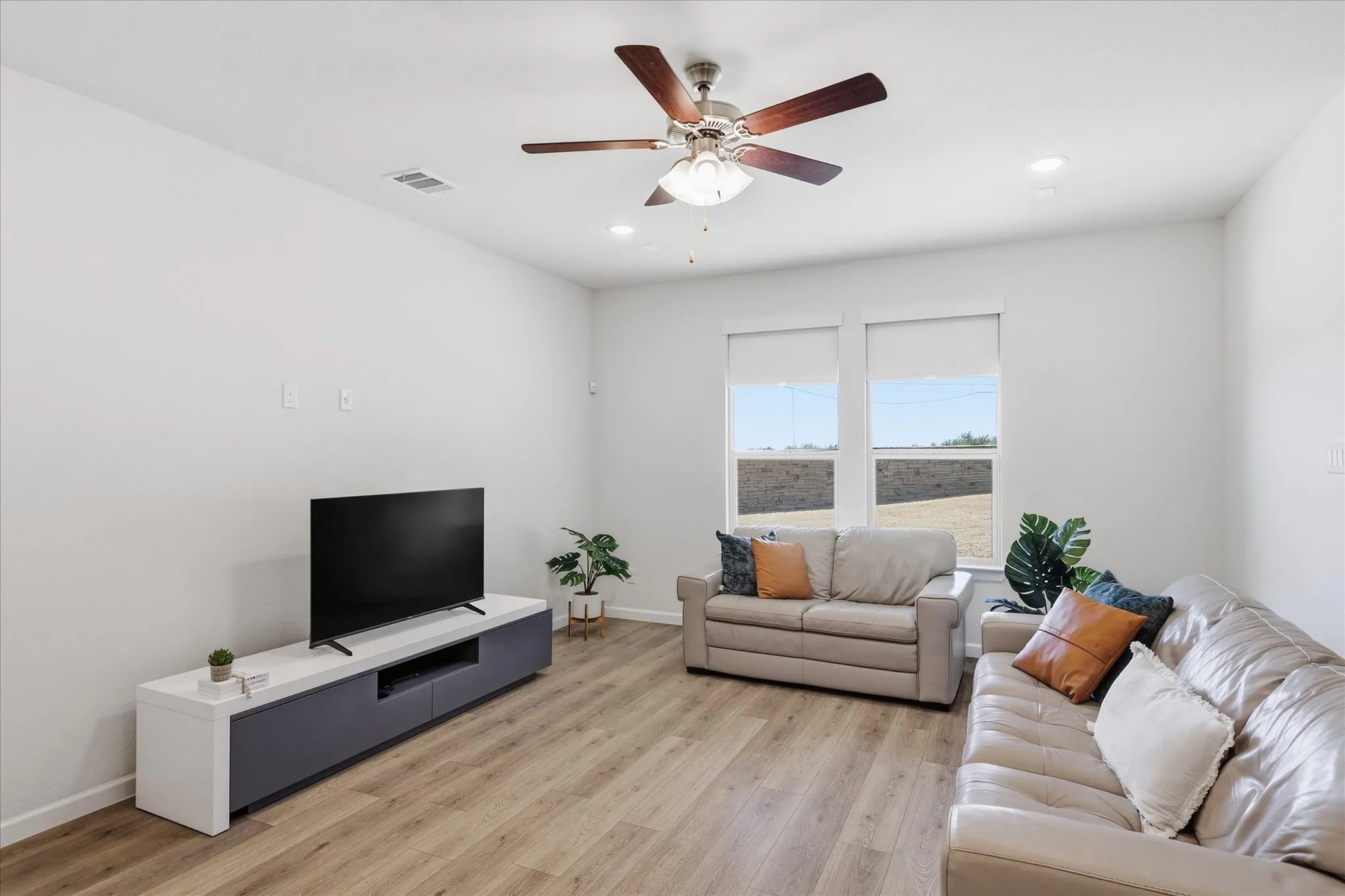 Recessed lighting, ceiling fan with wood-finish blades, wood-finish flooring, and dual windows with roller shades