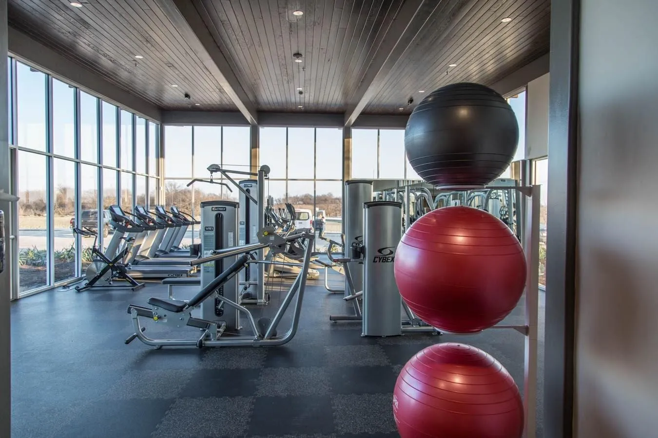Fitness facility featuring extensive exercise equipment, full-height windows, a wood-paneled ceiling, and recessed lighting