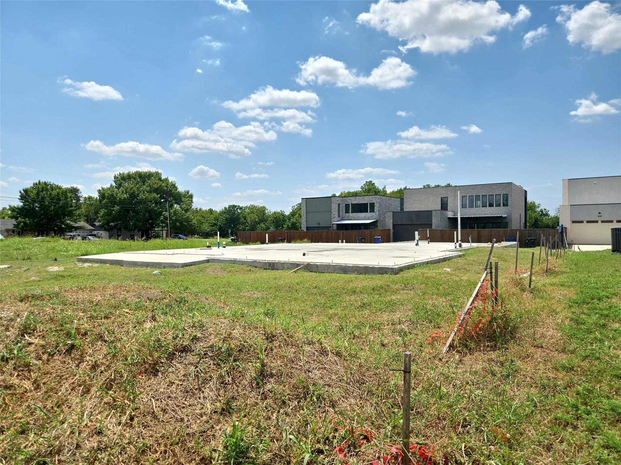 Concrete slab foundation with visible plumbing rough-ins, surrounded by an expanse of grass