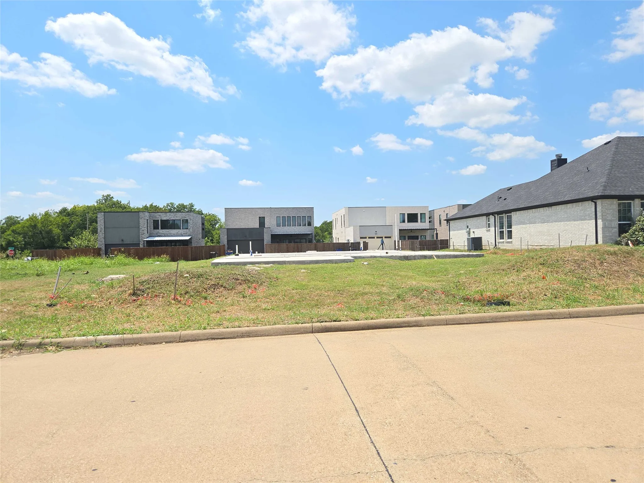 Level lot with an existing foundation, surrounded by contemporary and traditional architectural styles