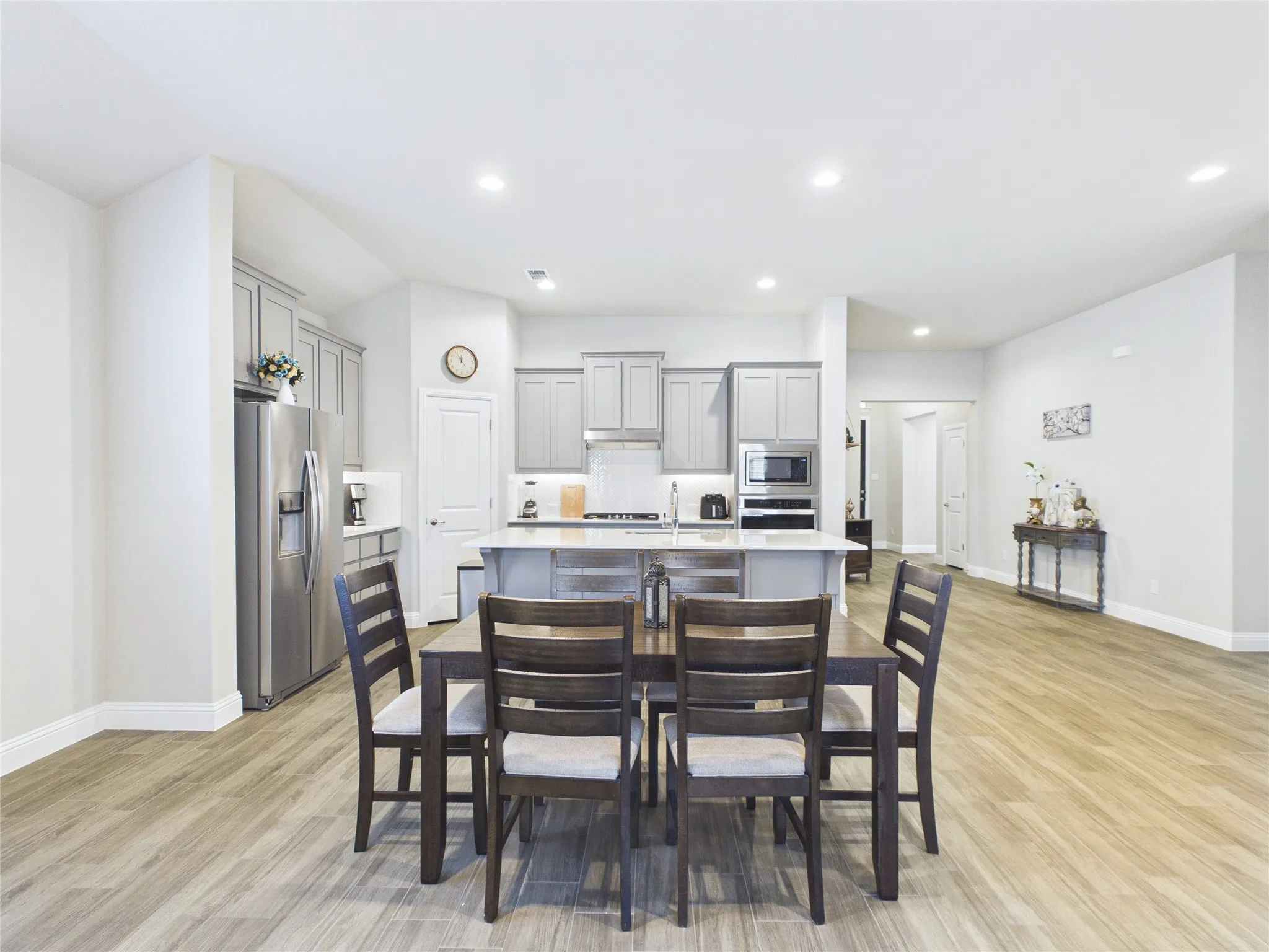 Open-concept living space with wood-finish flooring, recessed lighting, and a kitchen island with seating