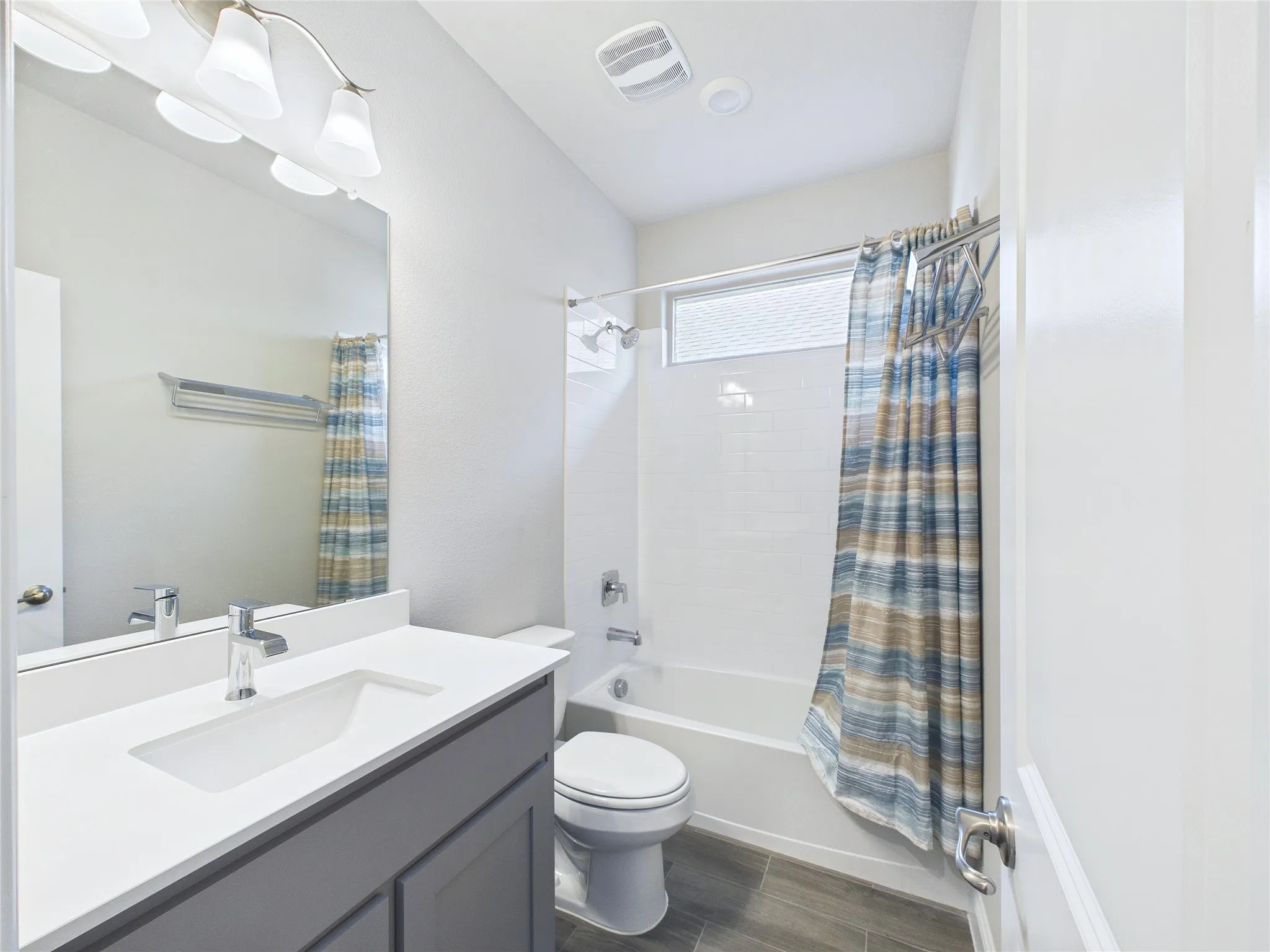 White vanity with an integrated rectangular sink, chrome faucet, and gray cabinetry