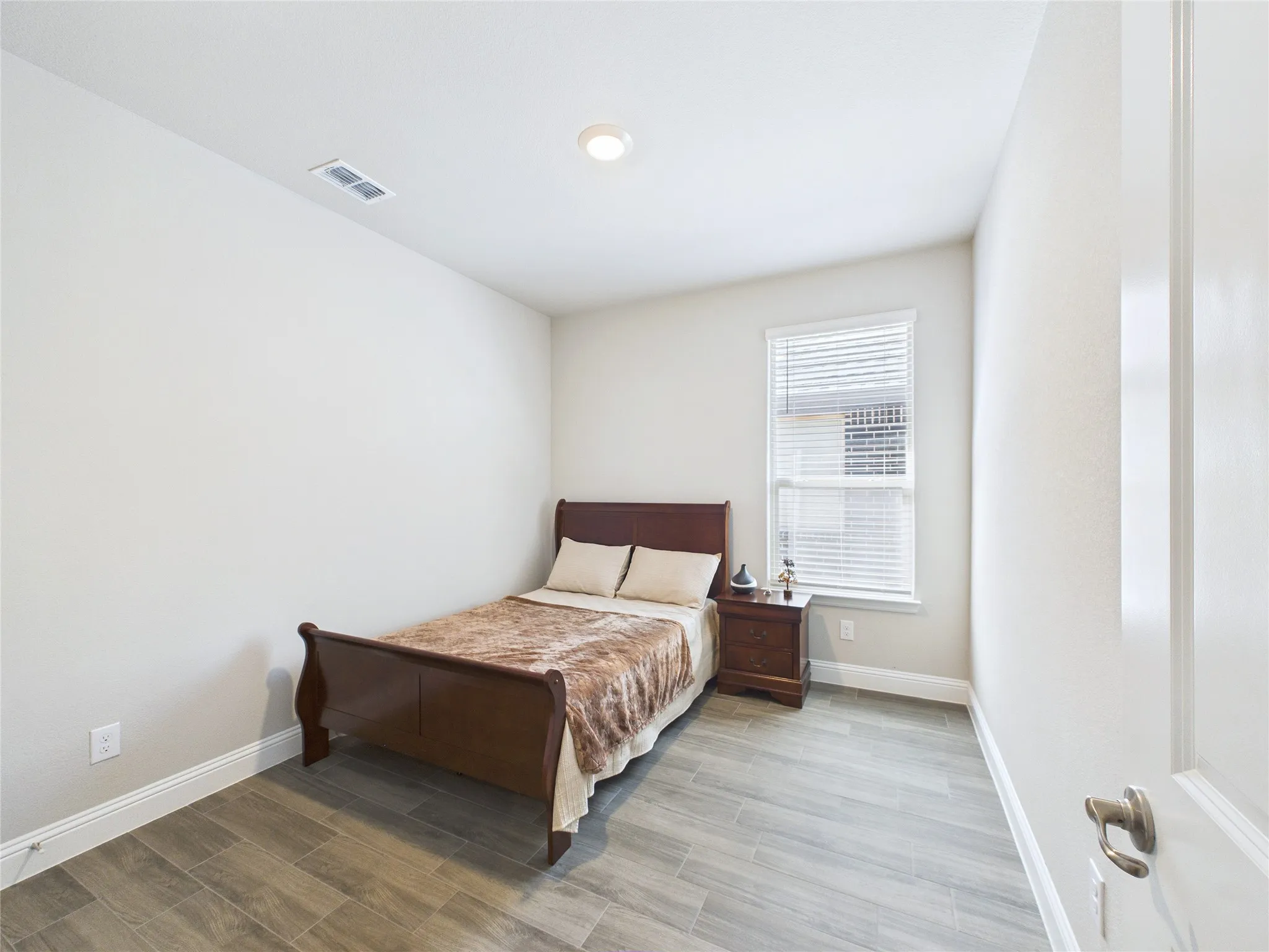 Recessed ceiling lighting, window with blinds, light-toned wall finishes, wood-finish flooring, and white trim