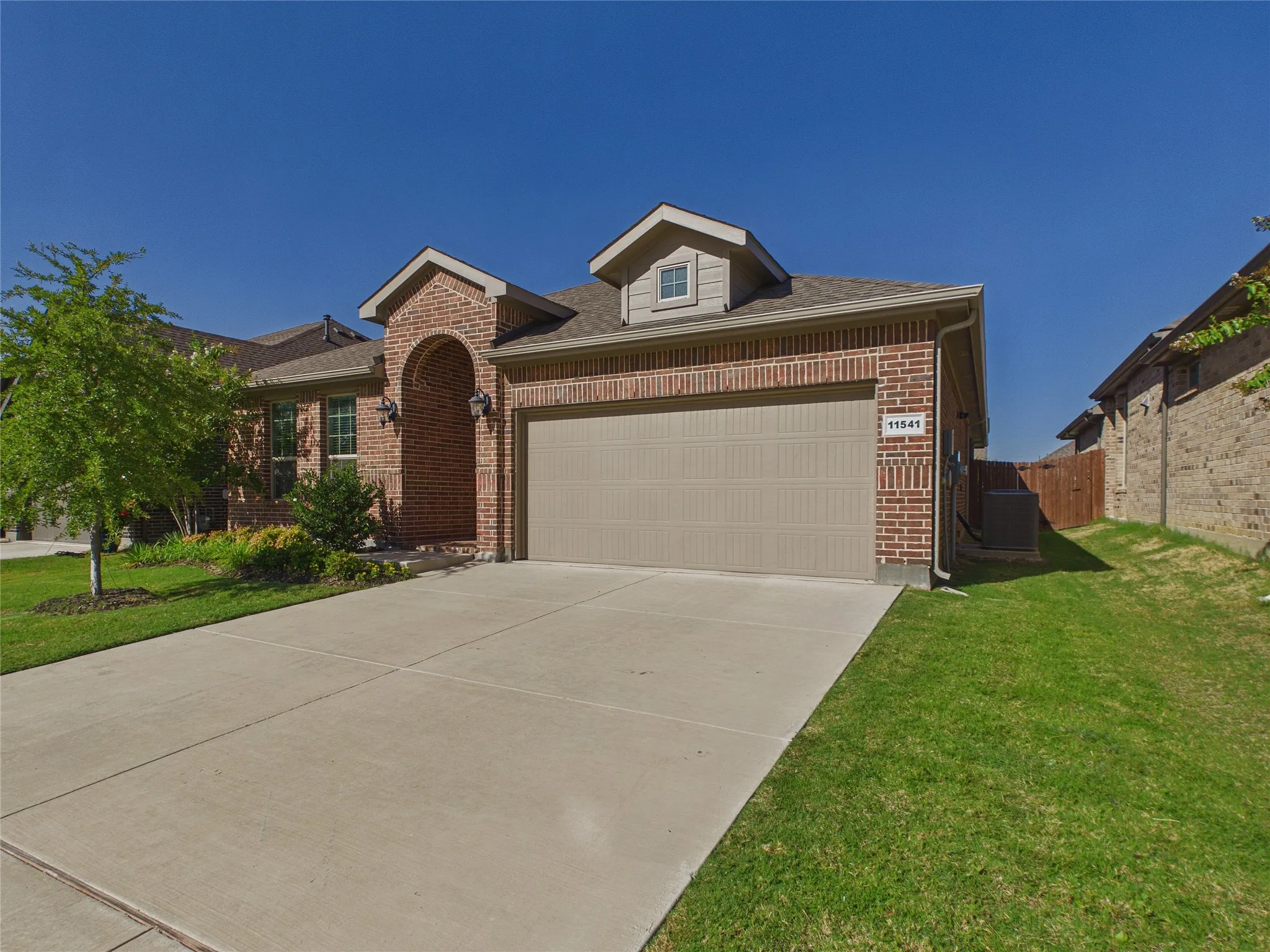 Brick exterior with stone accents, attached two-car garage, and concrete driveway