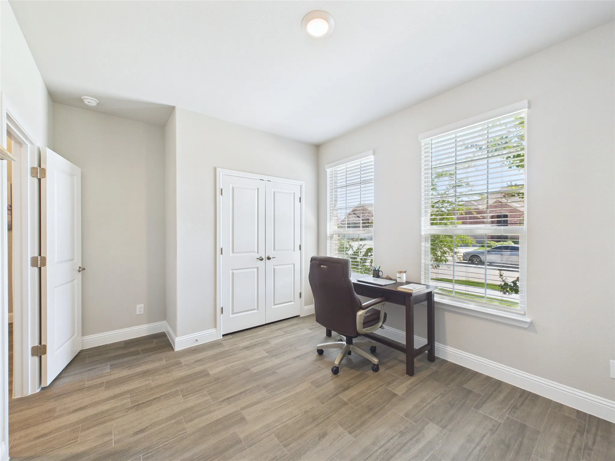 Recessed ceiling light, wood-finish tile flooring, dual panel doors, and window blinds