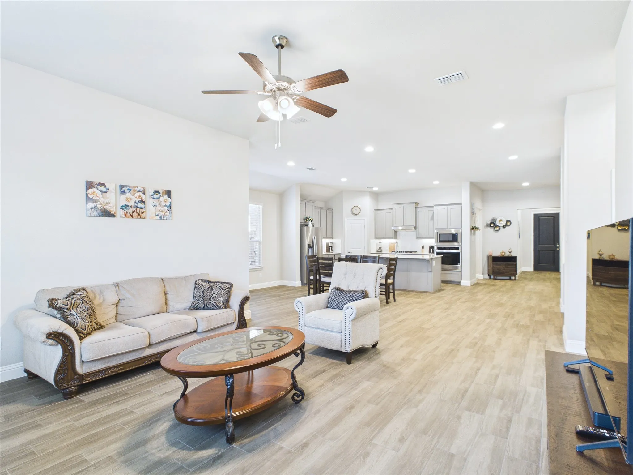 Open-concept living area featuring wood-finish flooring, recessed lighting, and a ceiling fan