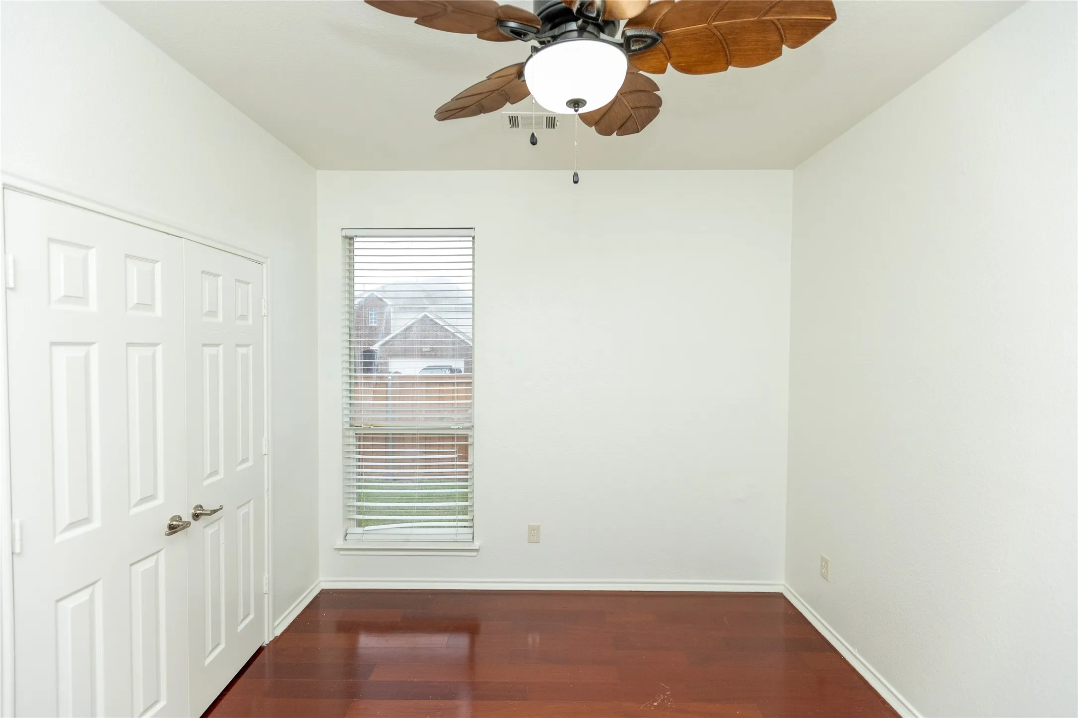 Wood-finish flooring, white paneled doors, ceiling fan with integrated lighting, and a window with blinds