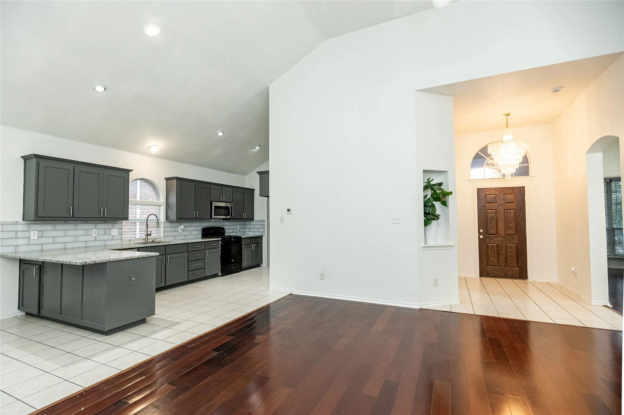 Vaulted ceilings complement the kitchen with dark-toned cabinetry, light-toned countertops, and a subway tile backsplash