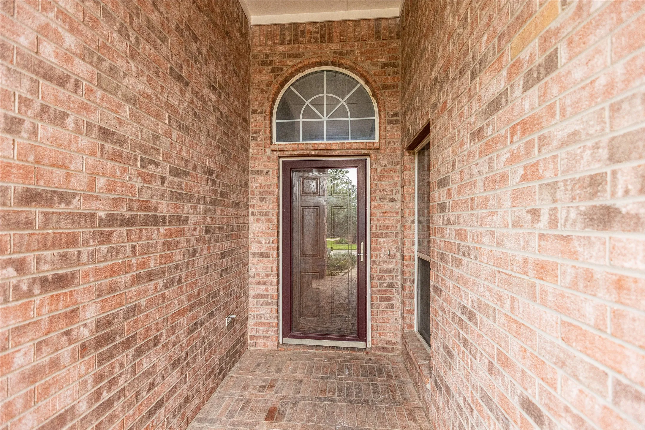 Brick exterior with a covered entry, arched transom window, and a glass-paneled front door