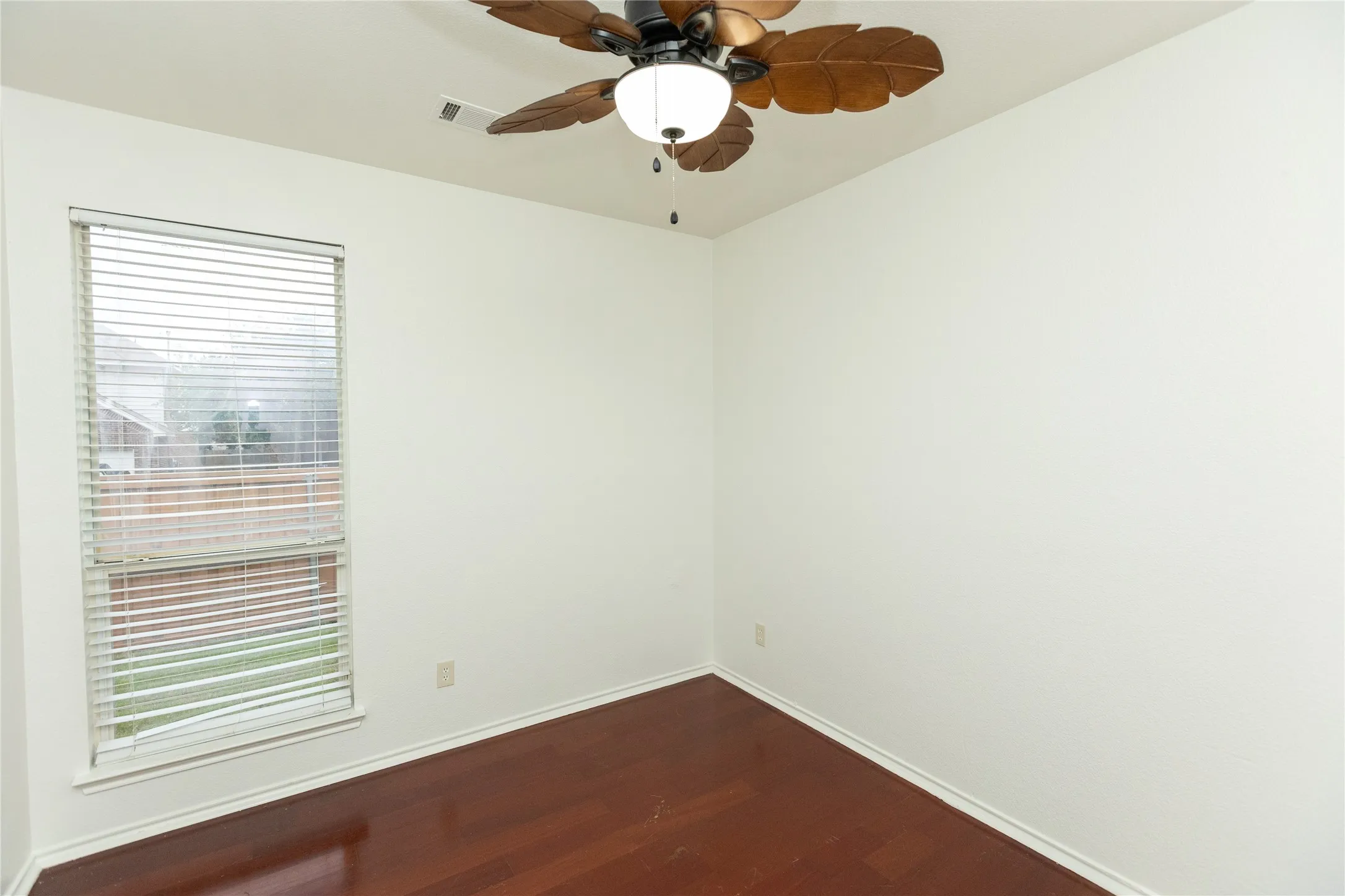 Wood-finish flooring, white walls, window with blinds, and a ceiling fan with light fixture
