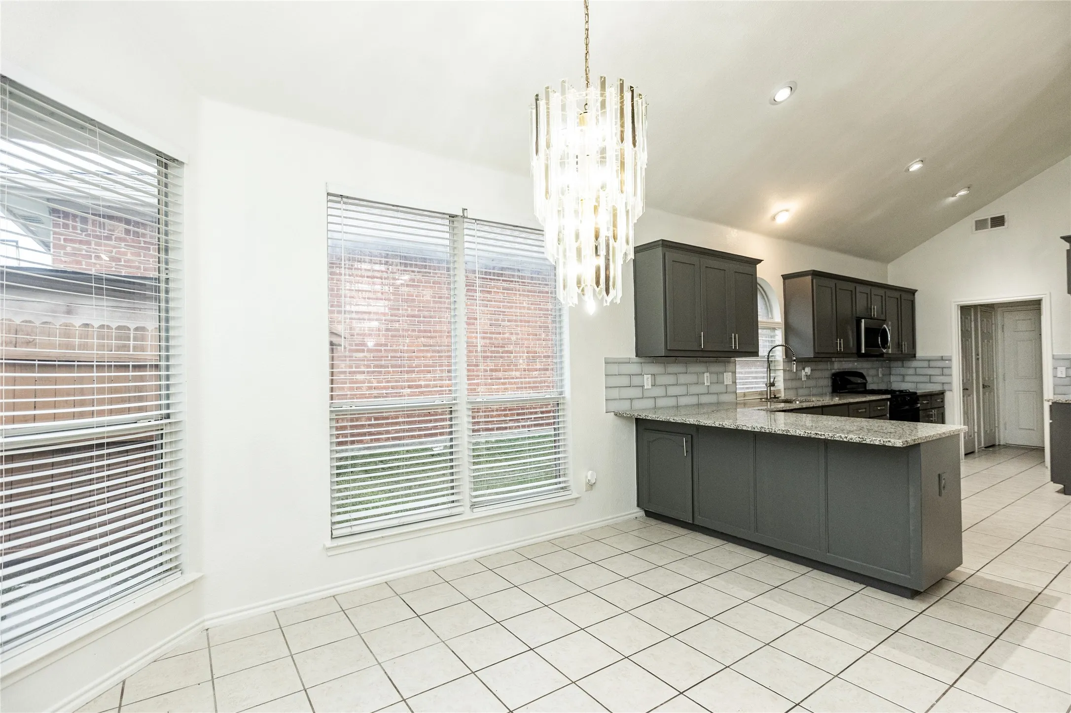 Kitchen featuring grey cabinetry, light-colored tile flooring, subway tile backsplash, and an island with a light-toned countertop