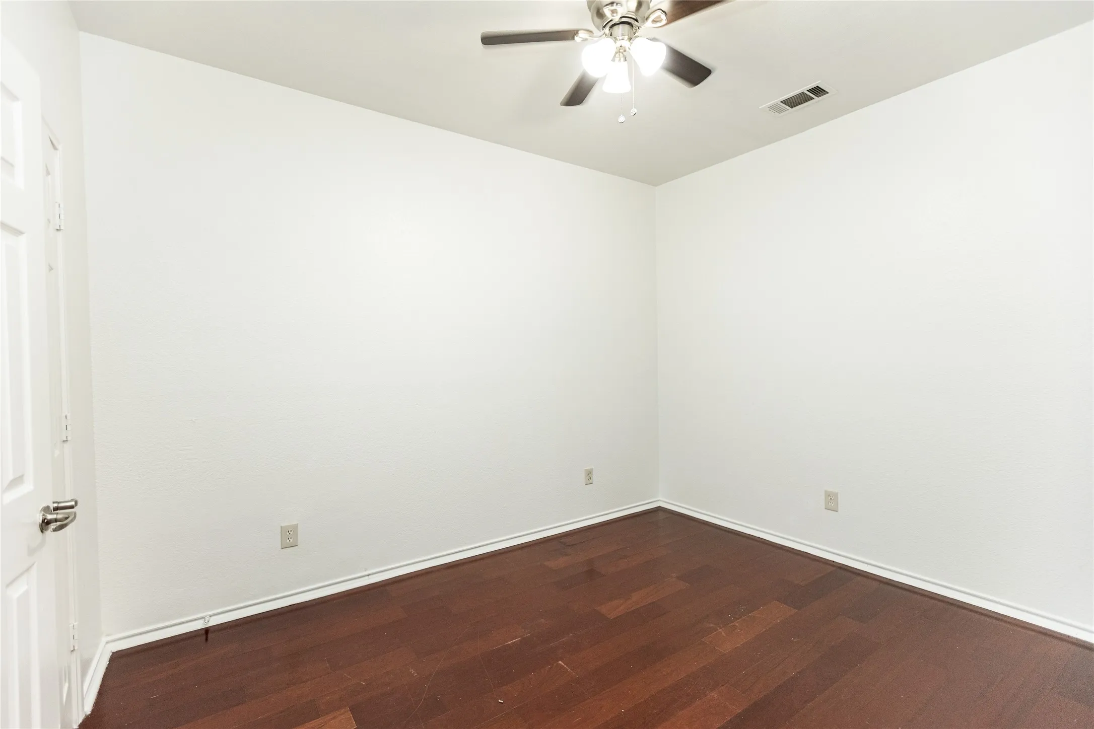 Wood-finish flooring, neutral wall tones, ceiling fan with integrated lighting, white paneled door
