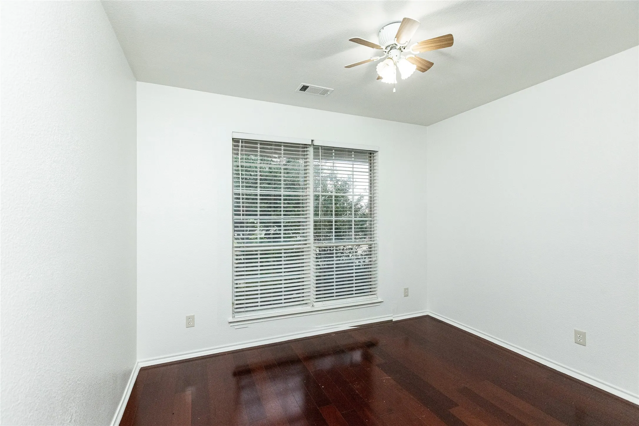 Wood-finish flooring, ceiling fan with integrated lighting, and a window with horizontal blinds