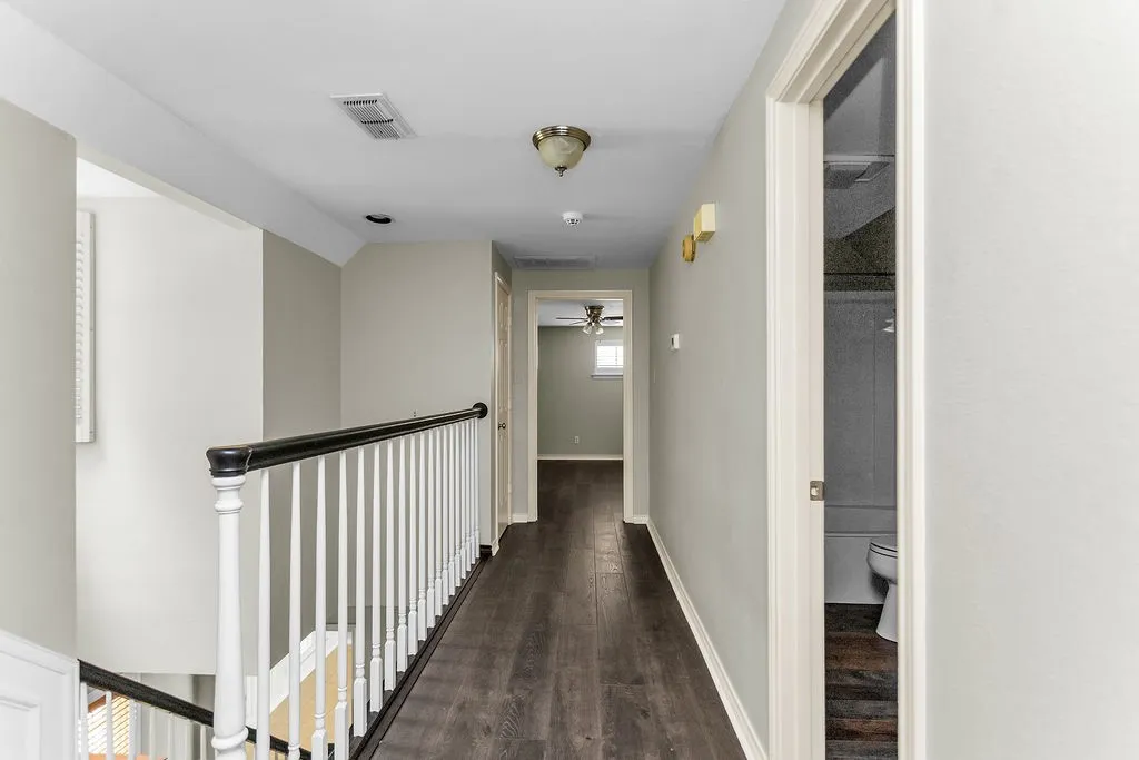 Hallway featuring dark wood-finish flooring, light-toned wall paint, and white trim