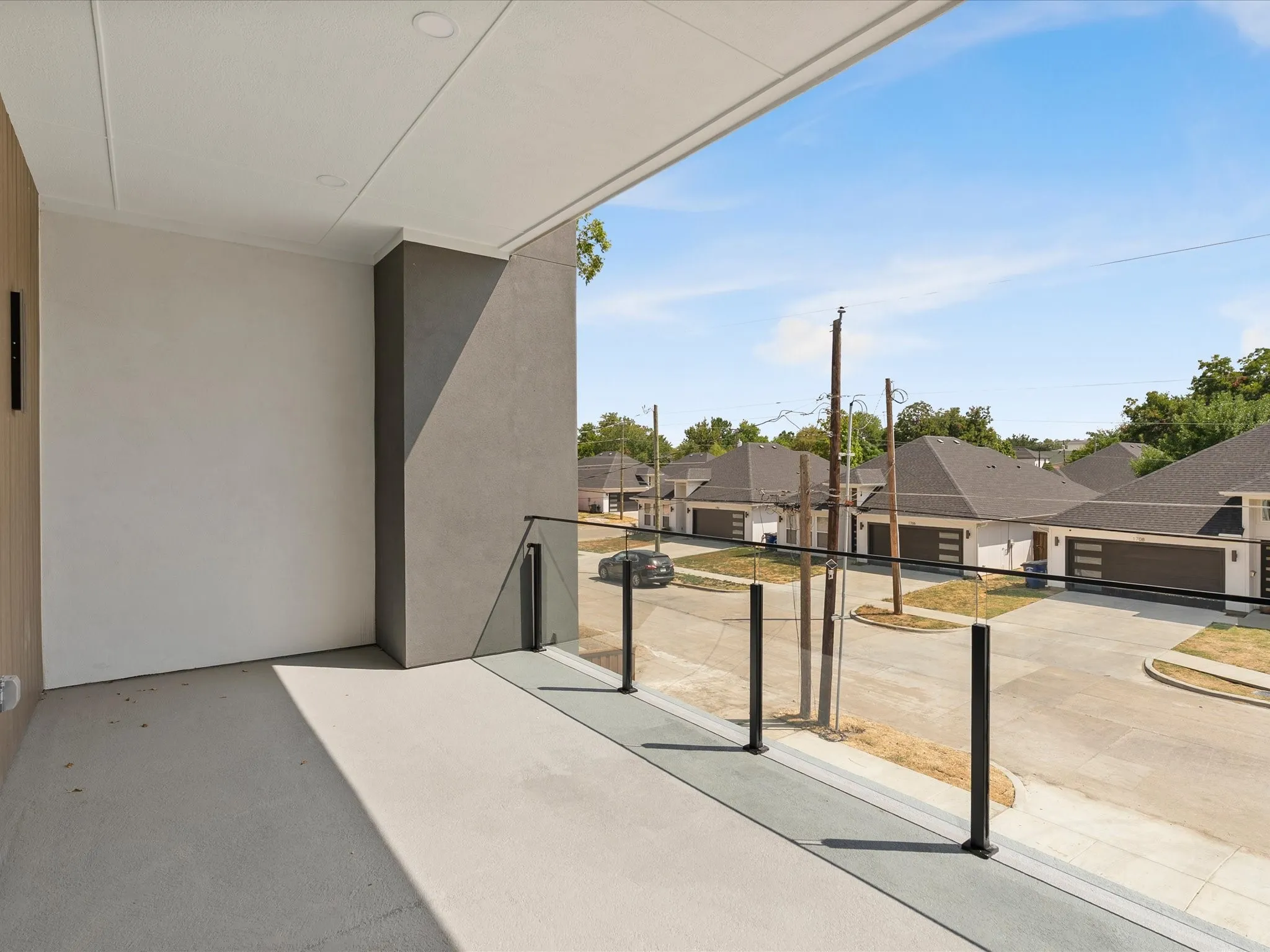 Outdoor balcony with a glass and metal railing, recessed ceiling lighting, and a durable concrete surface