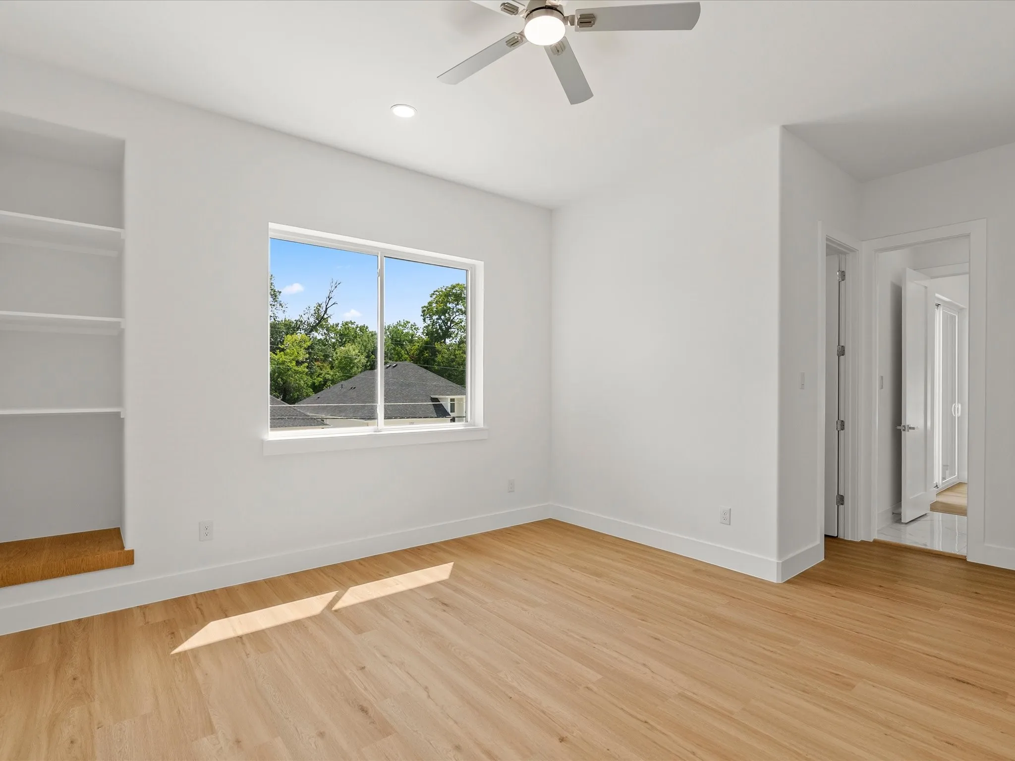 Luxury vinyl flooring, built-in shelving, white walls, recessed lighting, and a ceiling fan.