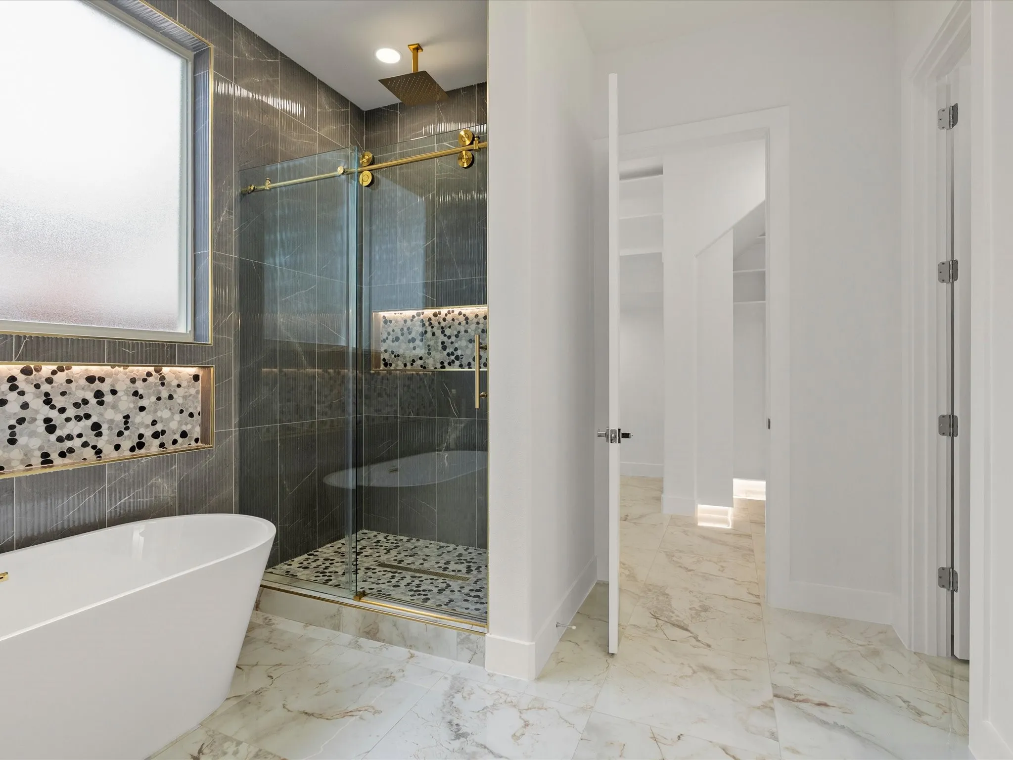 Freestanding soaking tub, walk-in shower with glass enclosure, gold-finish shower fixtures, porcelain tile flooring.