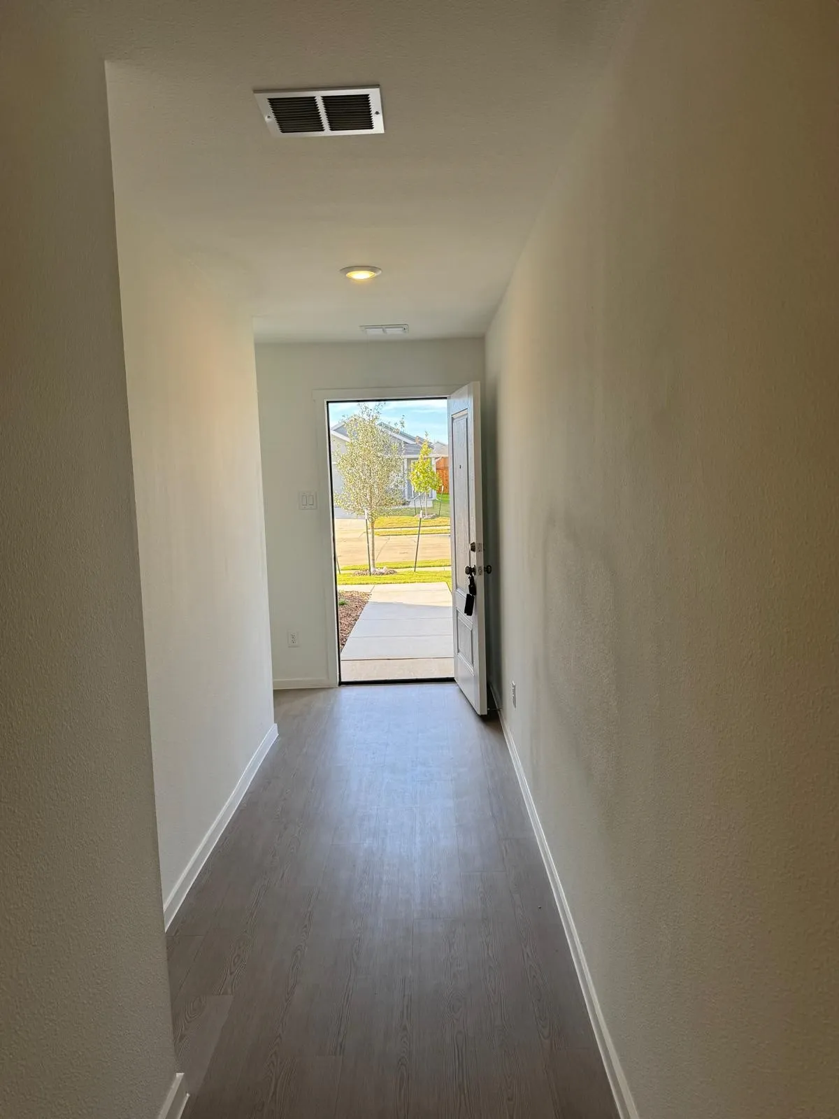 Corridor featuring dark wood-type flooring and a textured wall