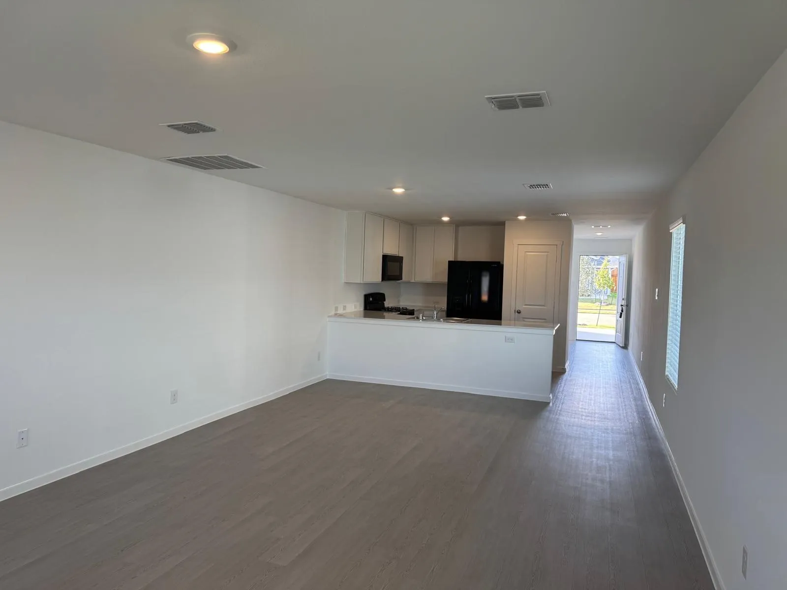 Kitchen featuring white cabinetry, open floor plan, black appliances, a peninsula, and light countertops