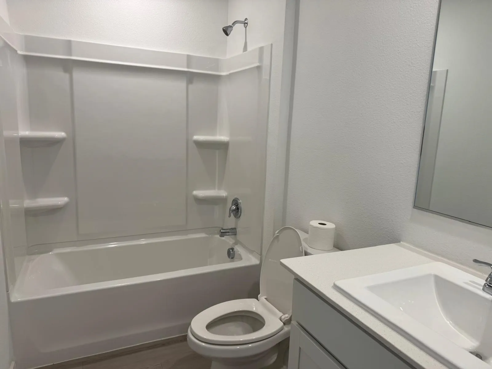 Full bath featuring vanity, a textured wall, bathing tub / shower combination, and wood finished floors