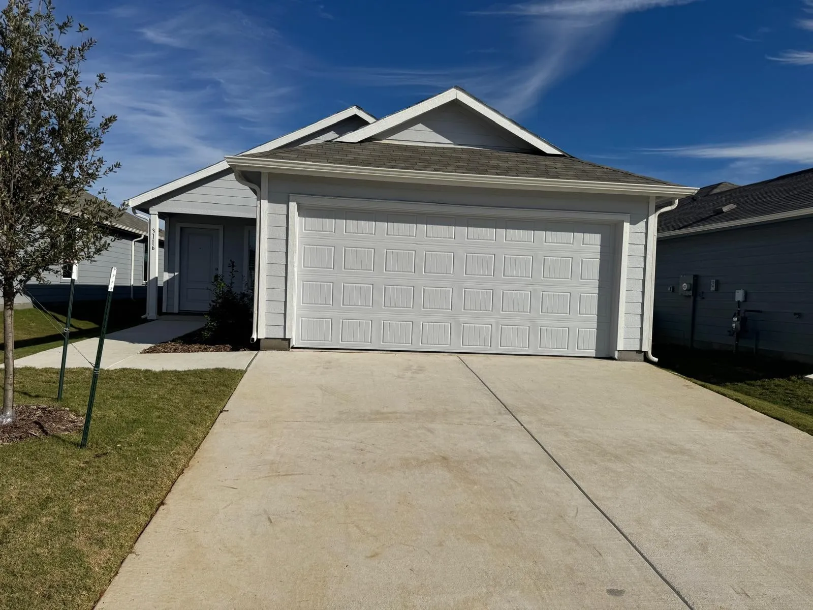 Single story home featuring driveway, a front yard, and an attached garage